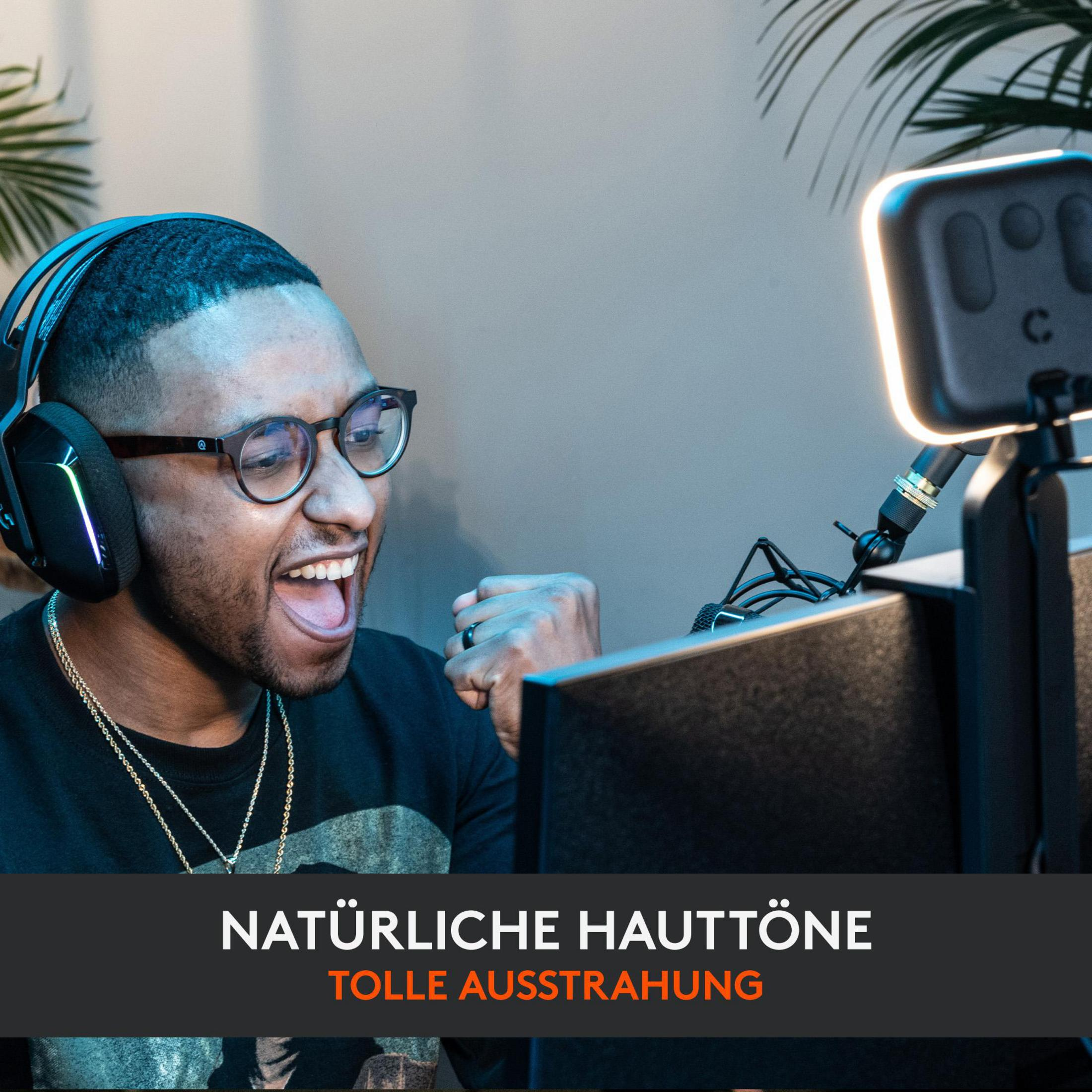 Hombre con auriculares, sonriendo, frente a un monitor con luz.