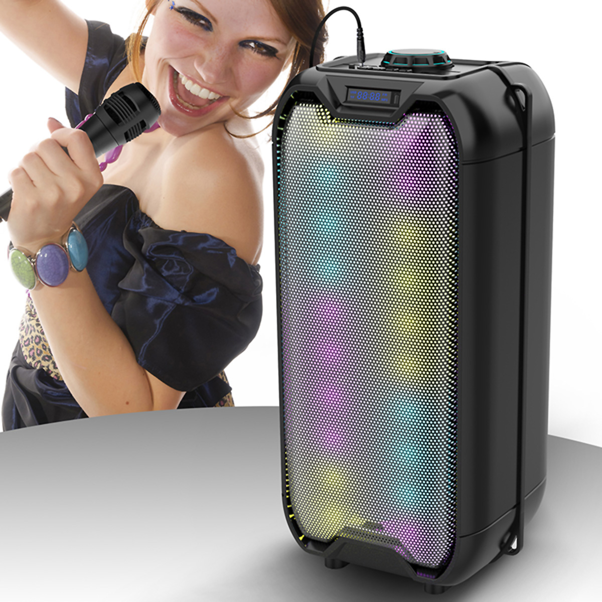 Una mujer cantando en un micrófono junto a un altavoz negro con luces de colores. Ella sonríe.