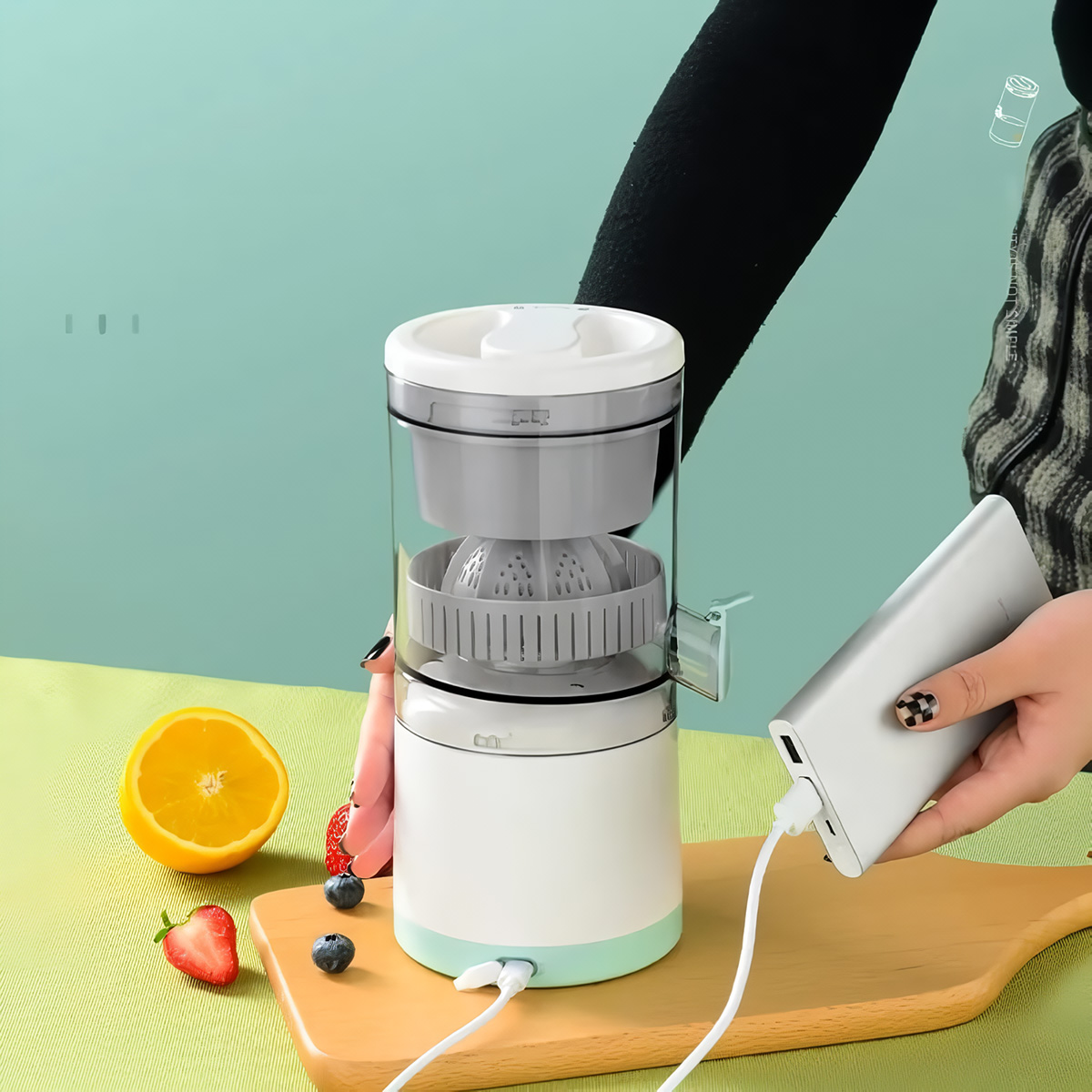Exprimidor con un recipiente transparente, naranja, fresas y un banco de energía plateado. El exprimidor es blanco y gris.