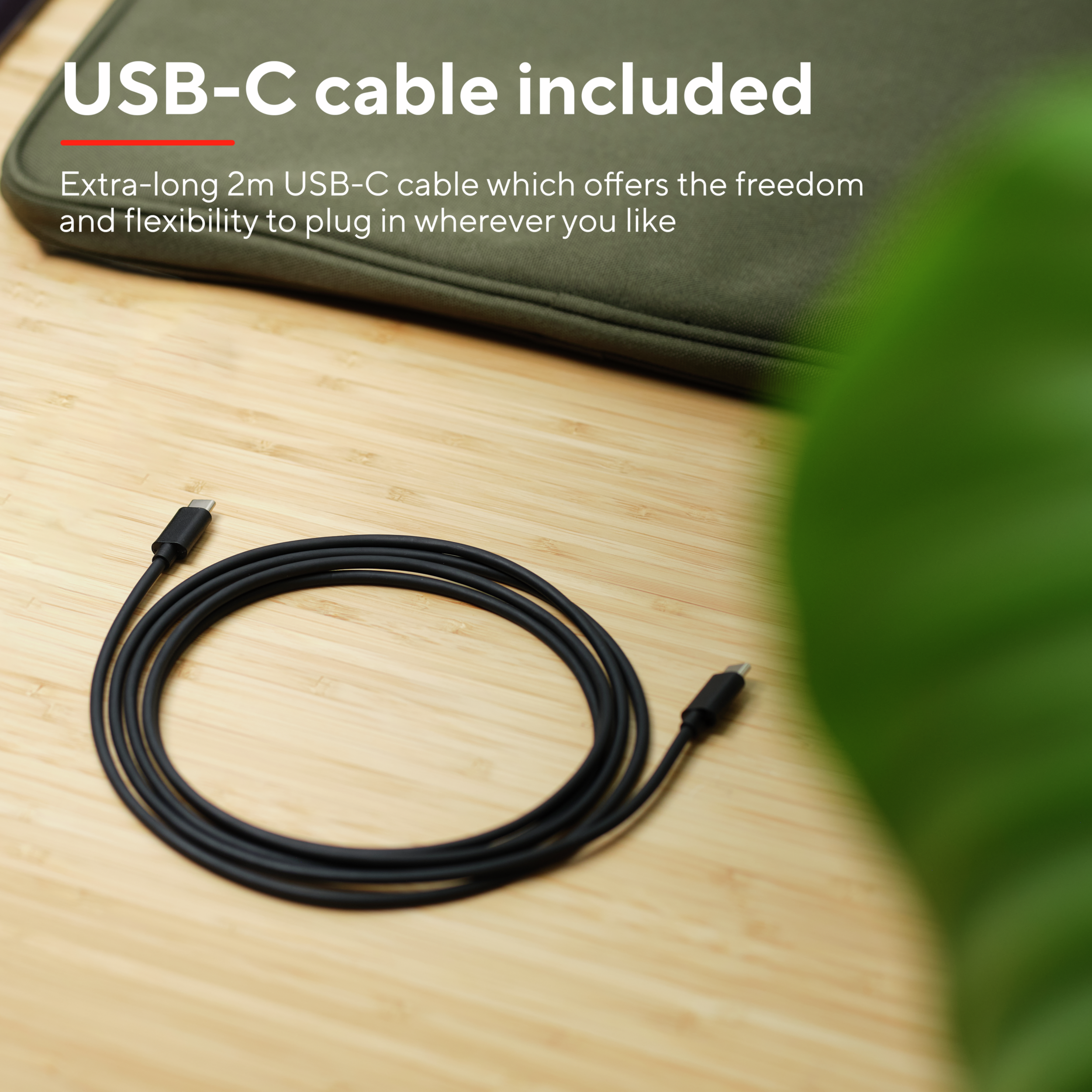 A black USB-C cable, coiled on a wooden surface with a green background.