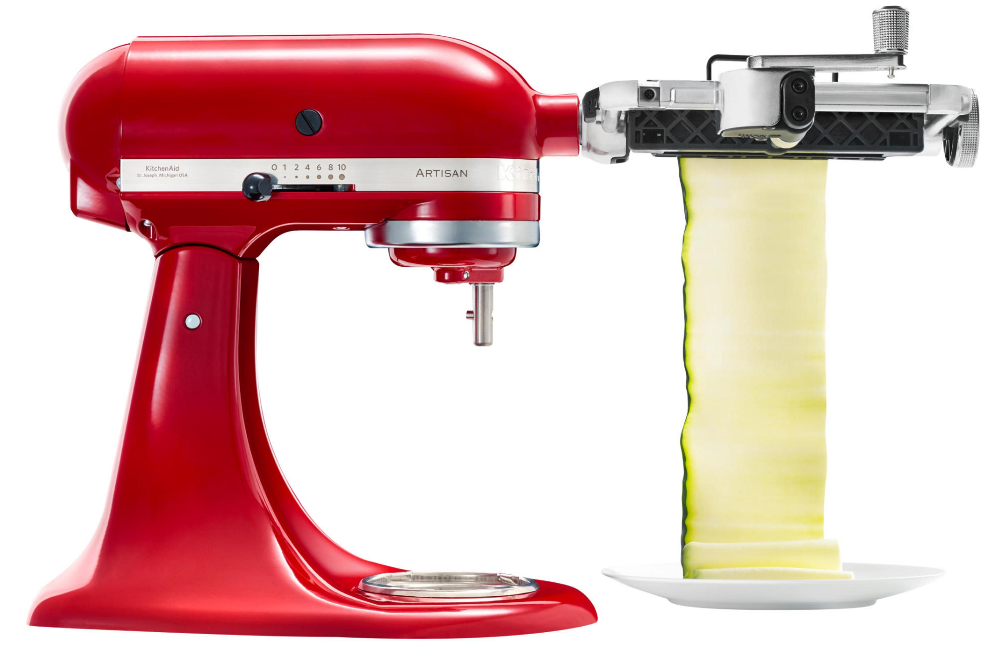 Ein roter KitchenAid-Mixer mit Spiralschneider-Aufsatz schneidet Zucchini auf einen weißen Teller.