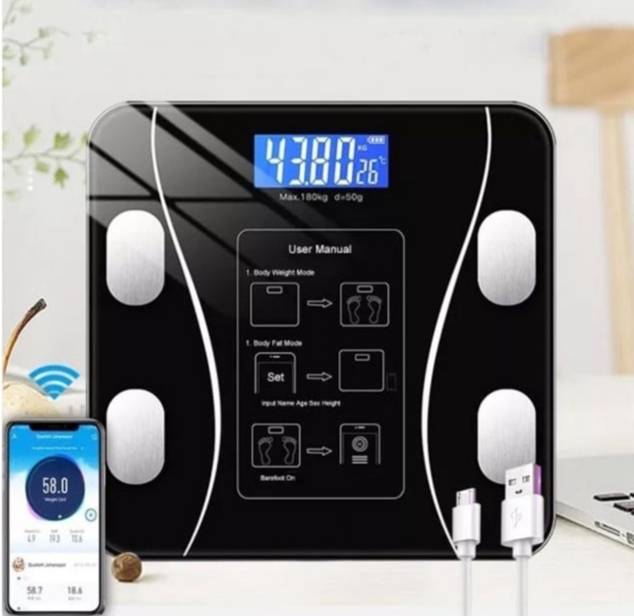 Báscula digital negra con teléfono que muestra el peso y un manual de usuario.