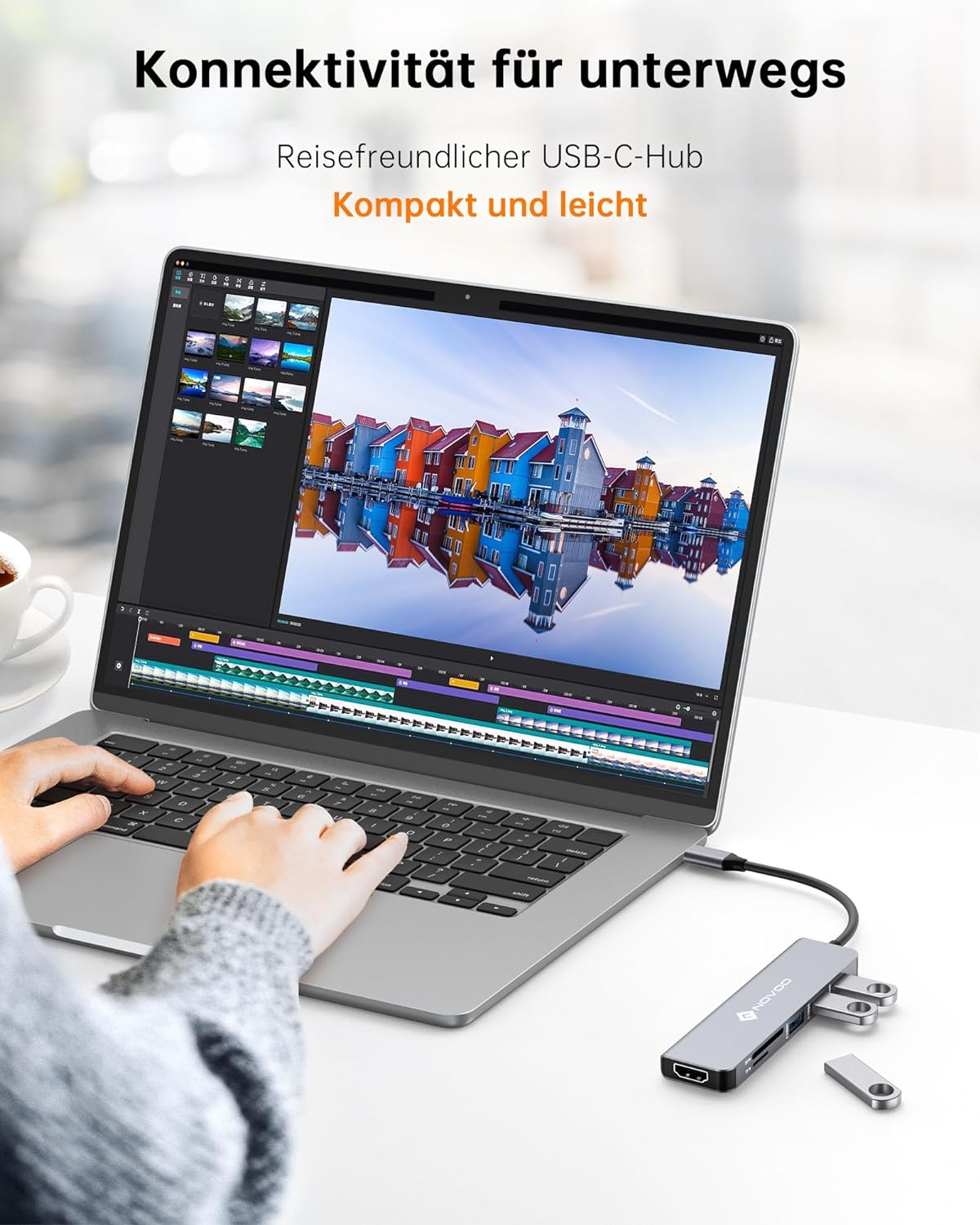 Hände einer Person auf einem Laptop. Ein USB-C-Hub mit verschiedenen Anschlüssen ist angeschlossen.