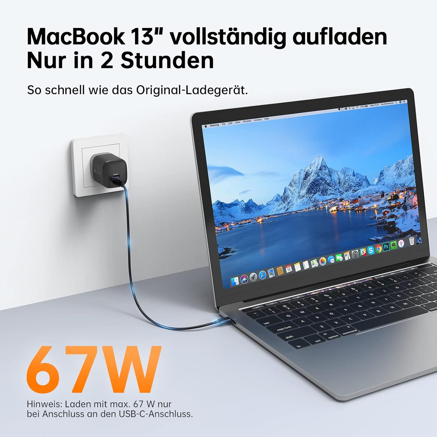 Ein Laptop wird geladen. Ein Stecker steckt in der Wand. Der Bildschirm zeigt Berge.
