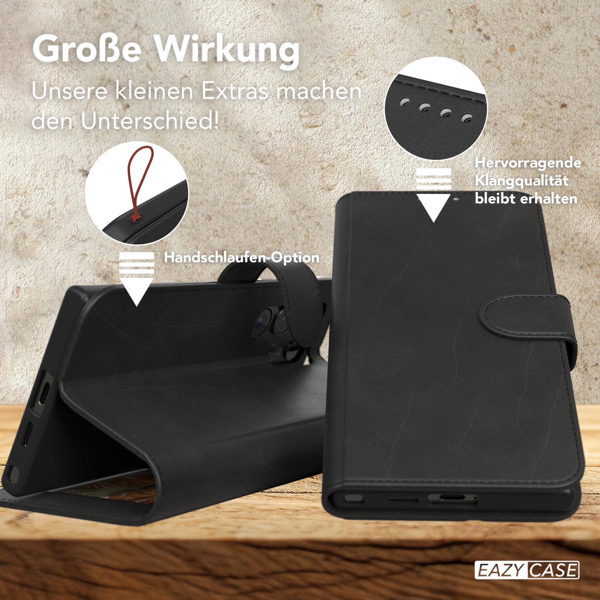 Geöffnete schwarze Handyhülle, die ein Telefon zeigt. Text und ein Riemen sind sichtbar. Hintergrund ist eine Holzoberfläche.