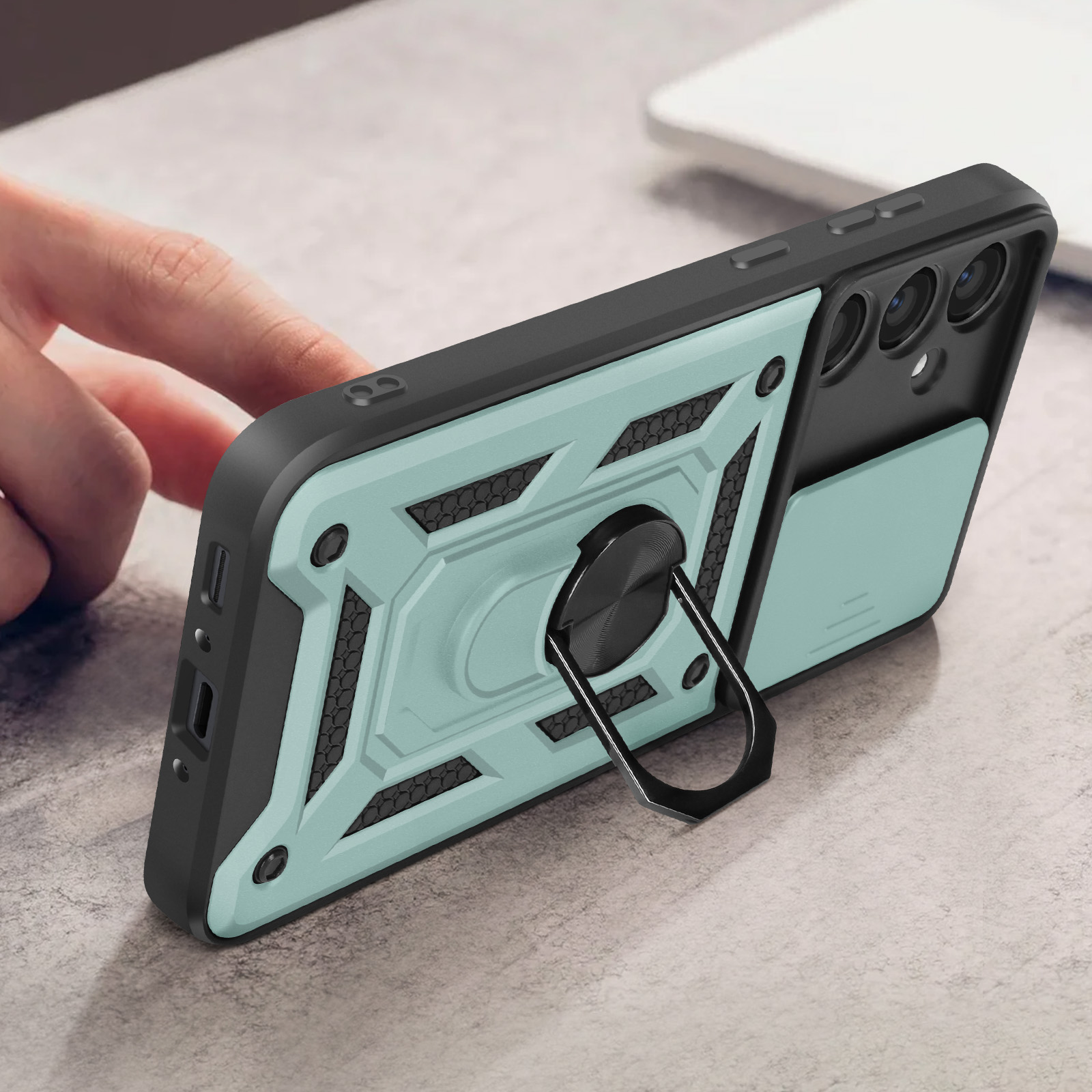 Una custodia per telefono con anello, turchese e nero, su un tavolo.