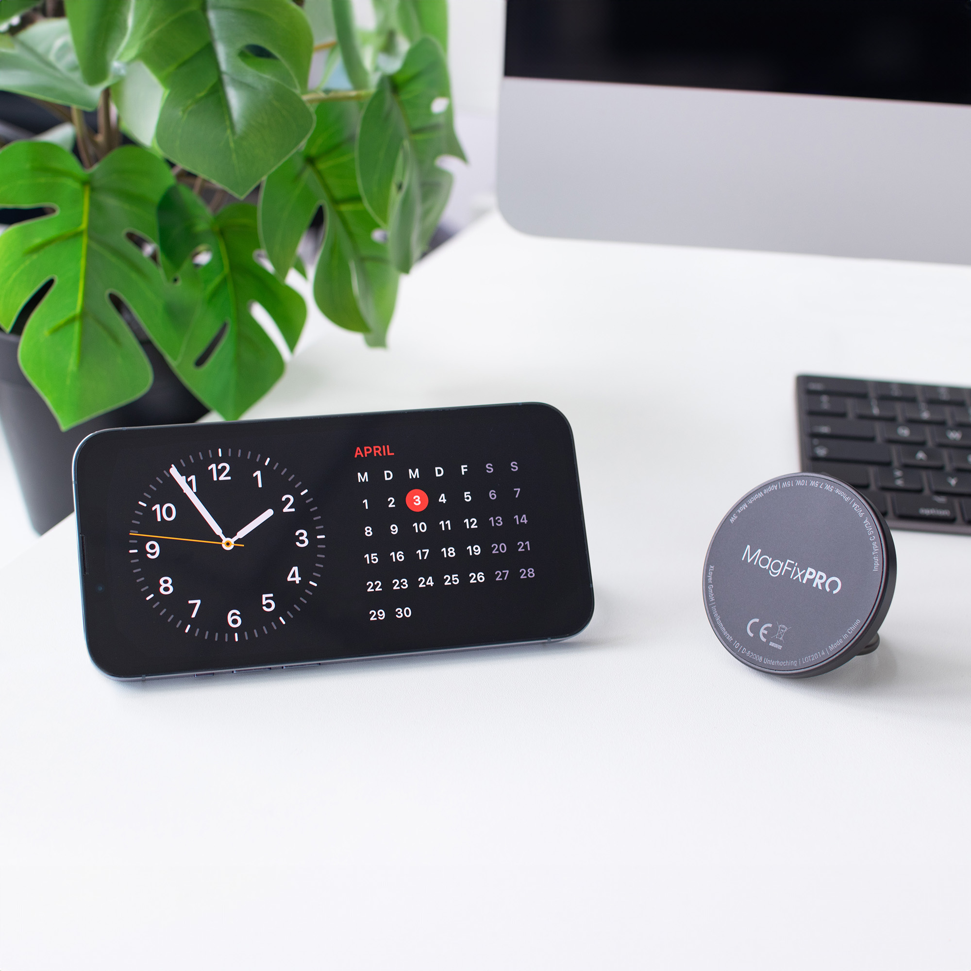 Schwarze Uhr mit Kalender, 3. April hervorgehoben. Schwarze Uhr, Kalender und ein magnetischer Telefonhalter.