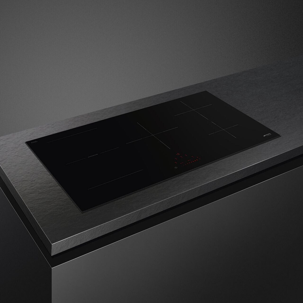 Un piano cottura nero integrato su un piano di lavoro scuro, con indicatori di cottura rossi.