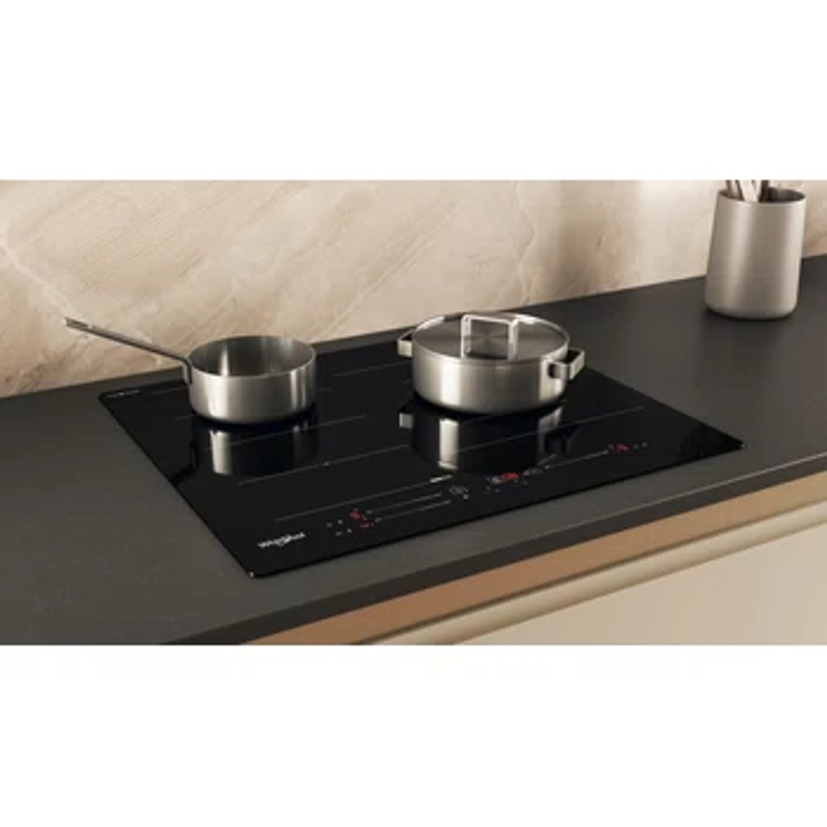 Czarna płyta grzewcza z dwoma garnkami. Znajduje się na ciemnym blacie.