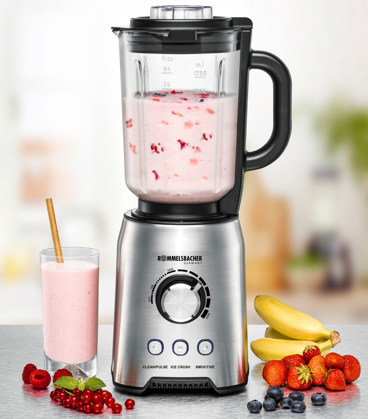 A stainless steel blender with a glass jar filled with pink smoothie and a glass of smoothie.