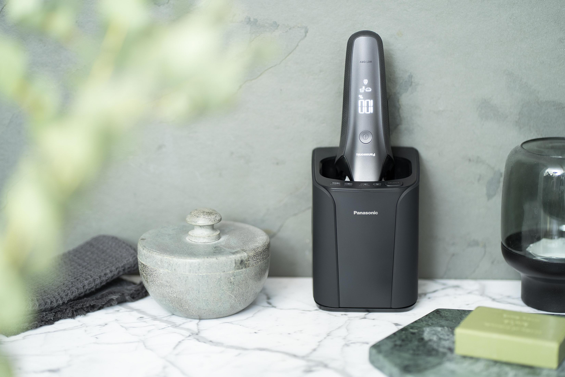 Nahaufnahme eines Badezimmer-Setups mit Rasierer in Ladestation und Zubehör.