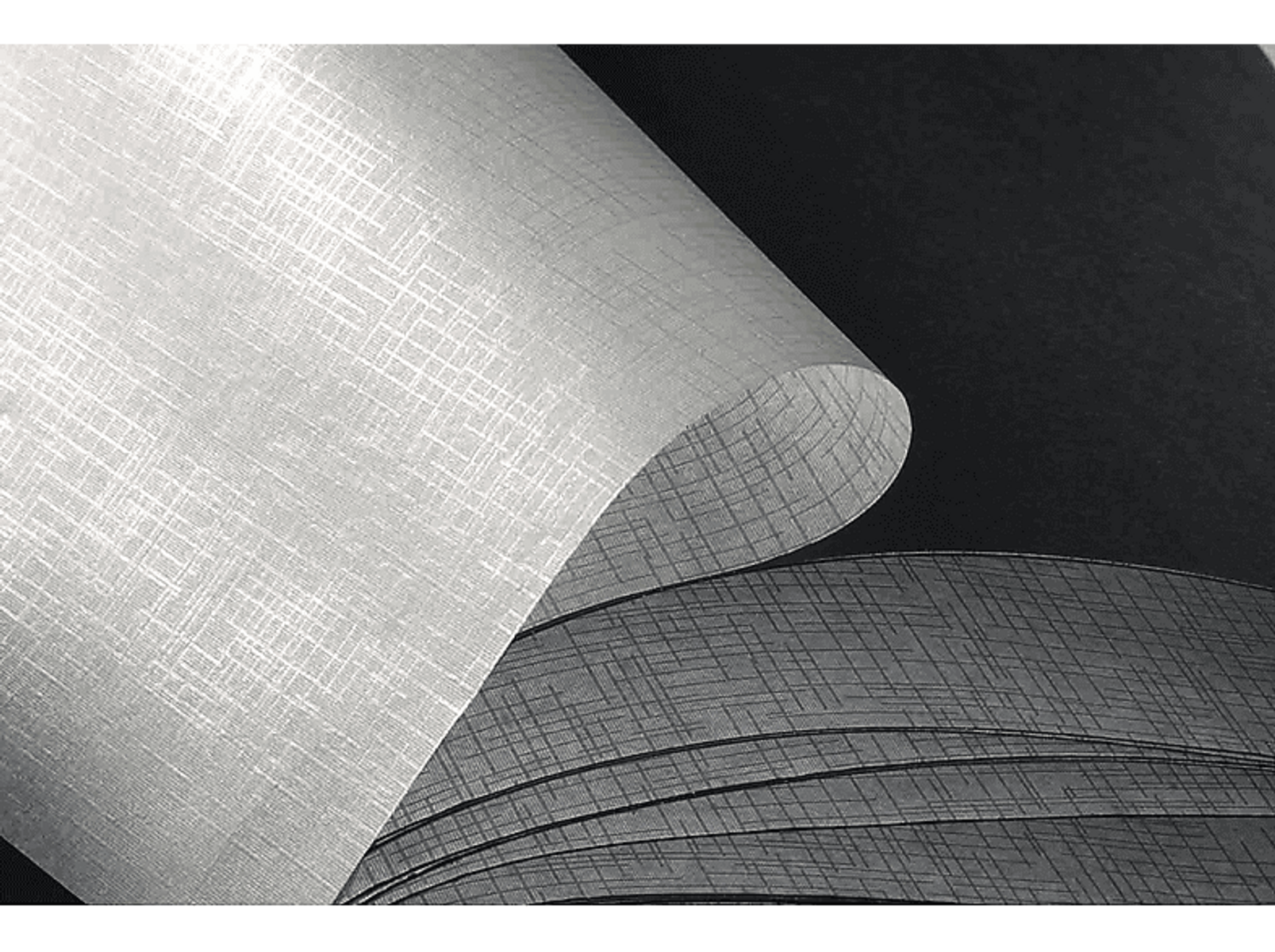 Białe i szare rolki tapet. Tapeta jest zwinięta, a tło jest czarne.