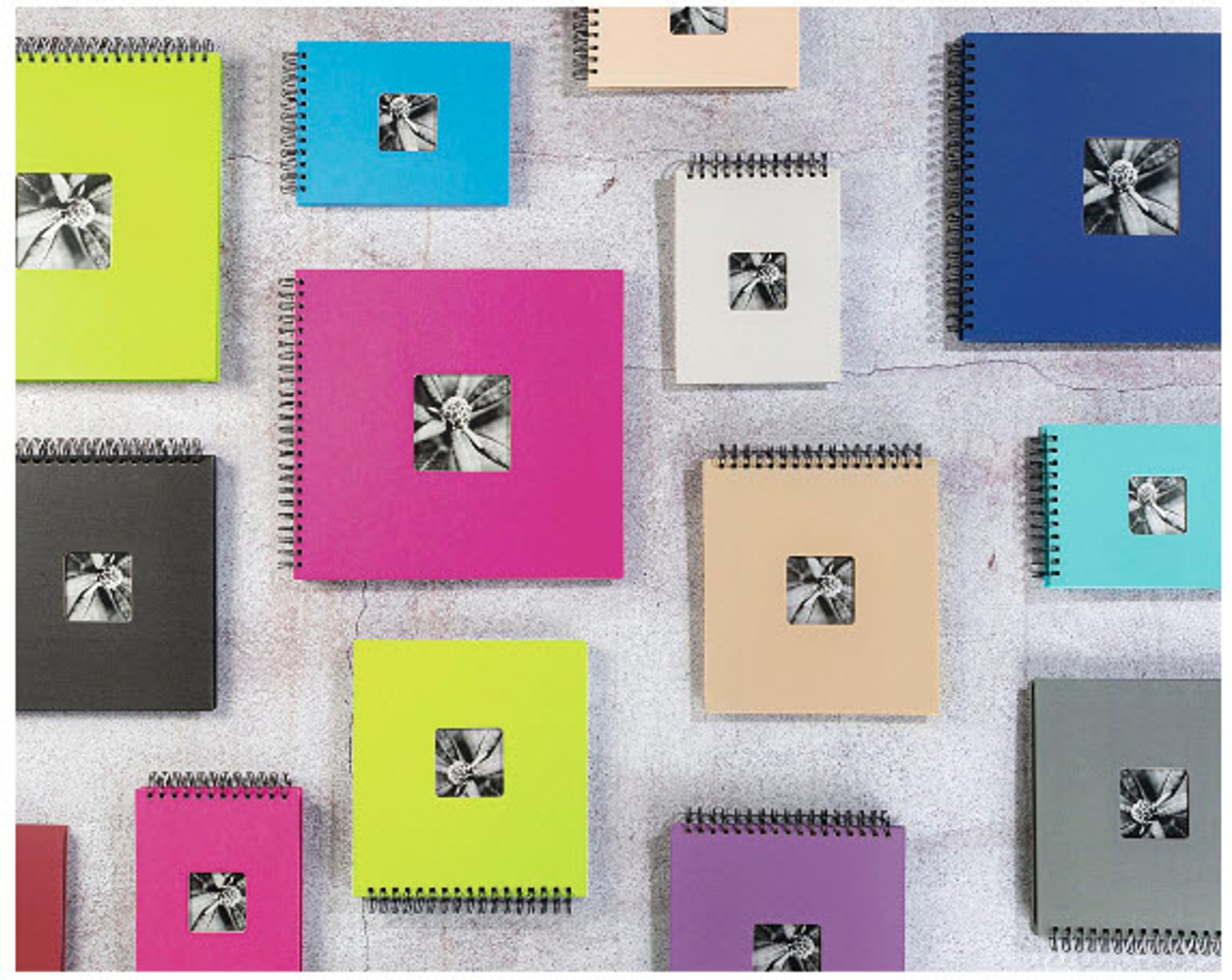 Kolorowe kwadratowe notatniki z kwiatowymi wkładkami fotograficznymi. Różne kolory, ułożone na ścianie.