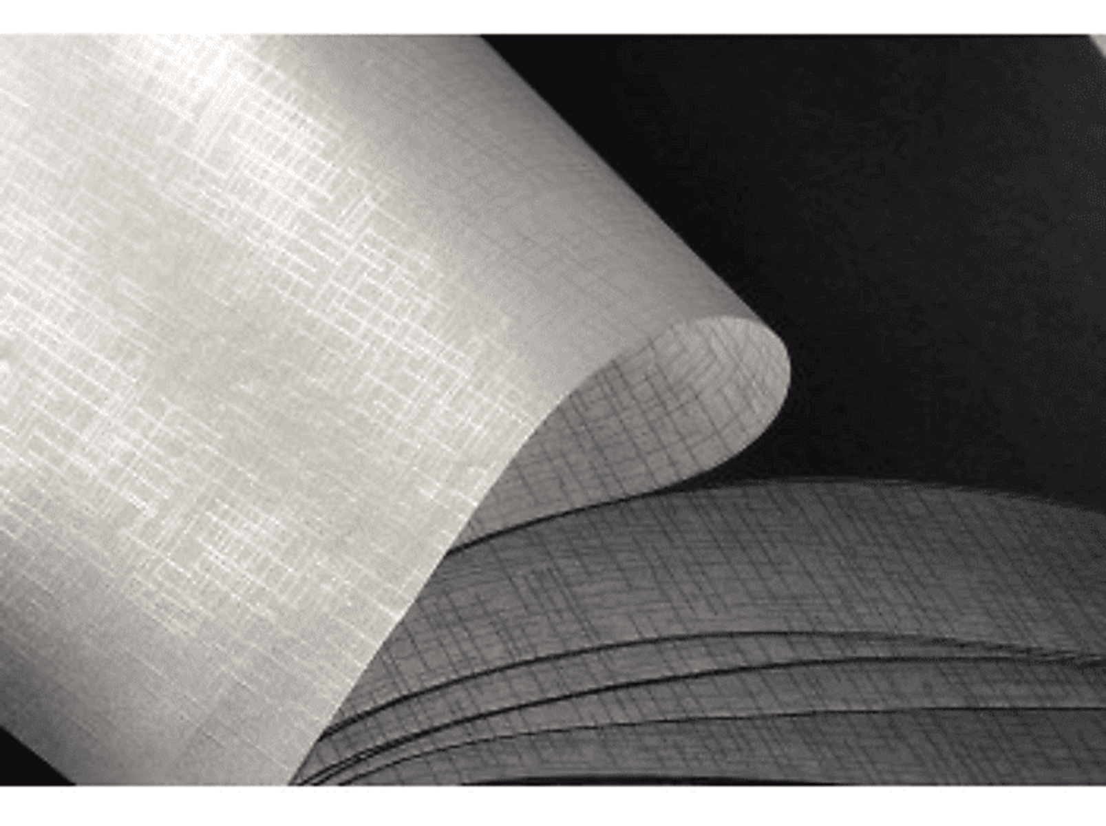 Zbliżenie zwiniętego, teksturowanego papieru, tworzącego zakrzywiony, warstwowy efekt w skali szarości.