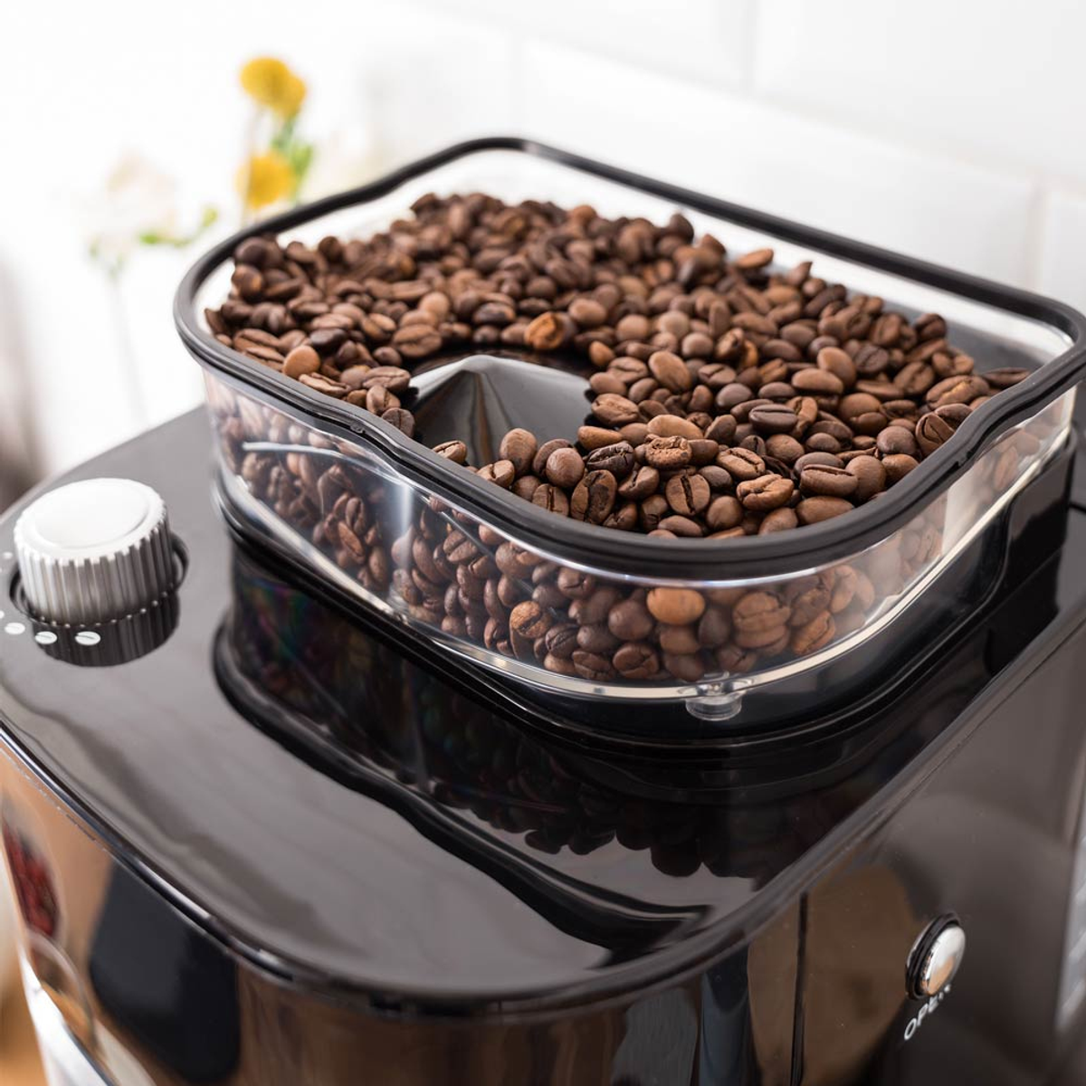 Una macchina per il caffè nera con un contenitore trasparente pieno di chicchi di caffè.