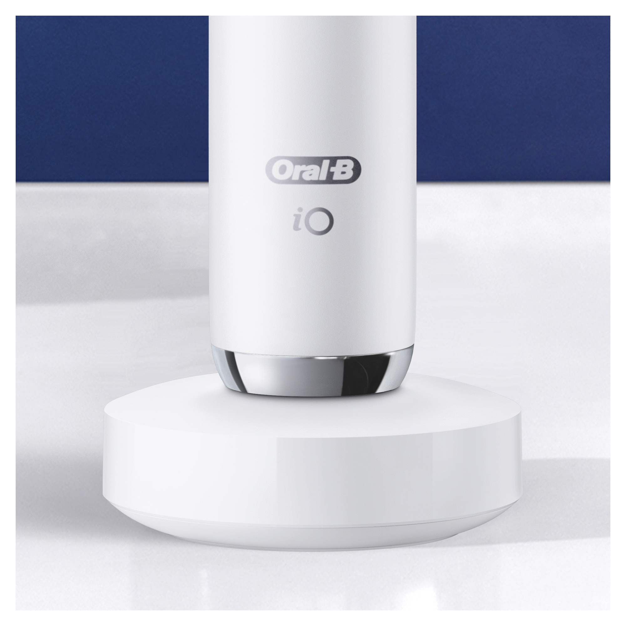 Cepillo de dientes Oral-B iO blanco sobre una base de carga blanca, fondo azul y blanco.