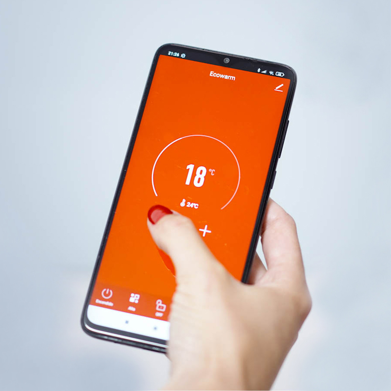 Persona sosteniendo un smartphone con pantalla naranja de temperatura de 18 grados.