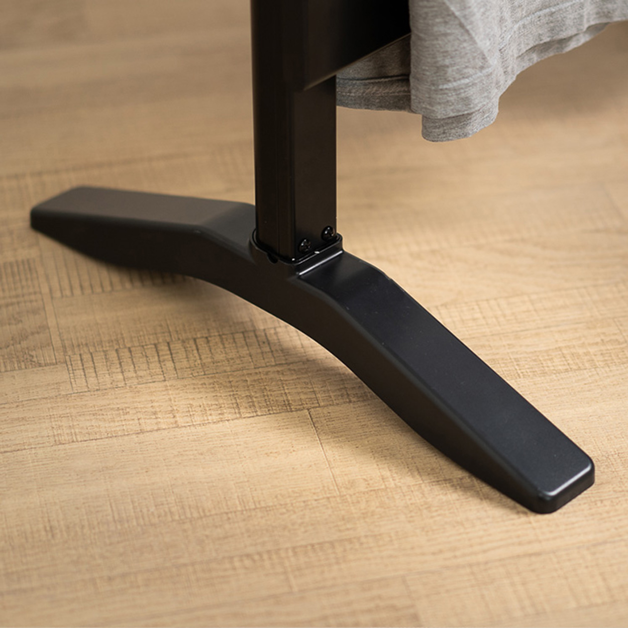 Base negra y angular de un escritorio o mesa, sobre un piso de madera clara.