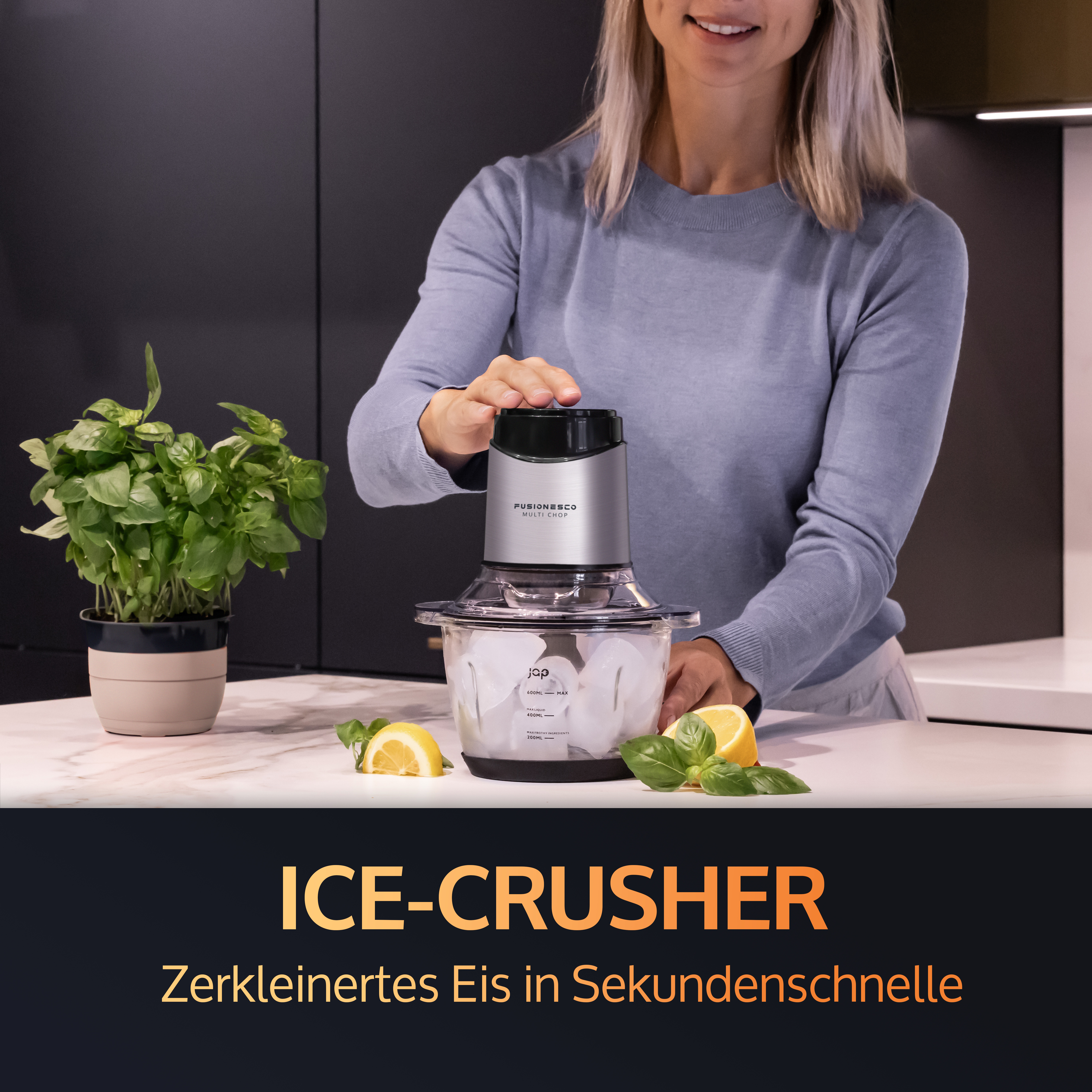 A woman uses an ice crusher. The device is black and silver, with ice and lemons beside it.