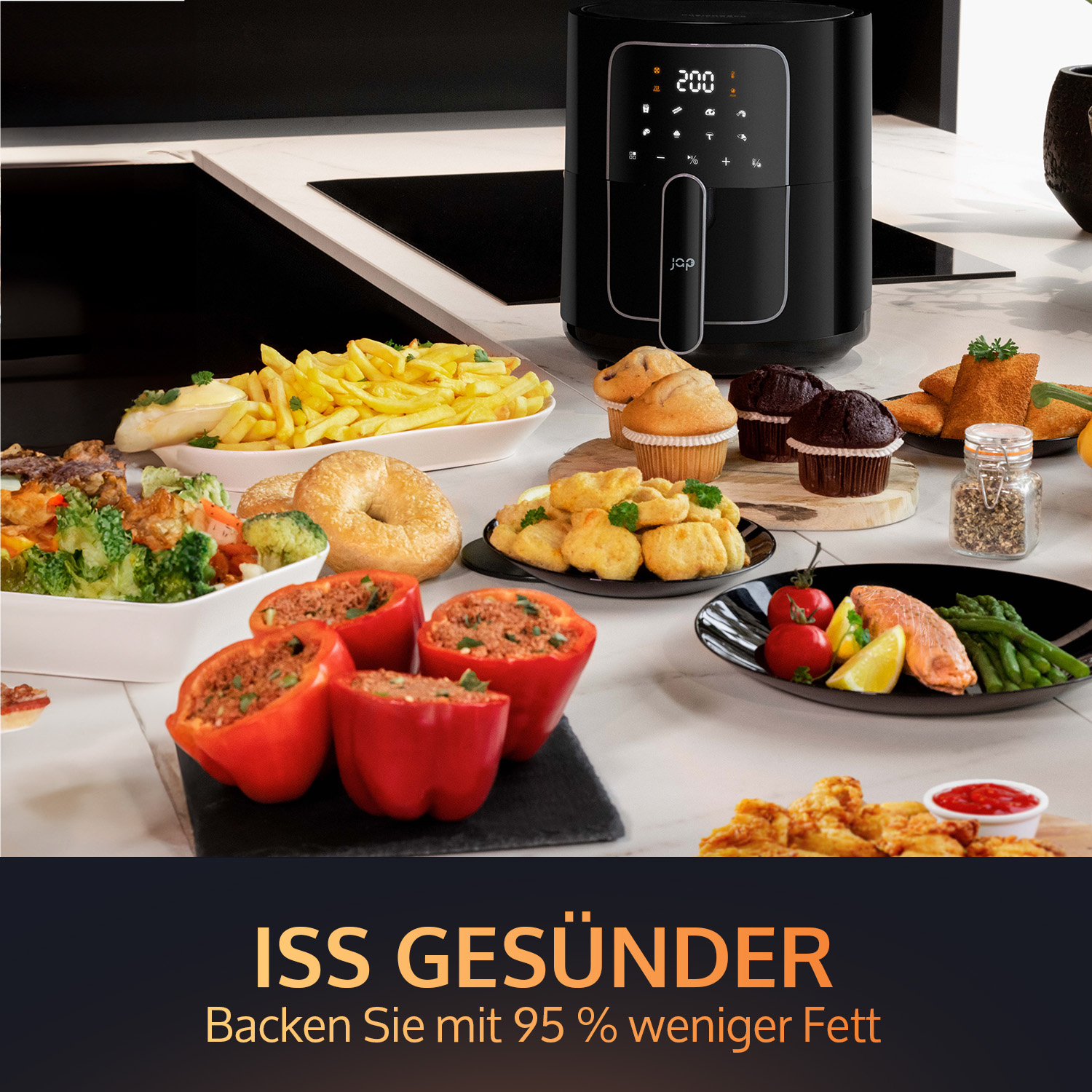 Black air fryer with food. Food includes french fries, muffins, vegetables, and stuffed peppers on a table.