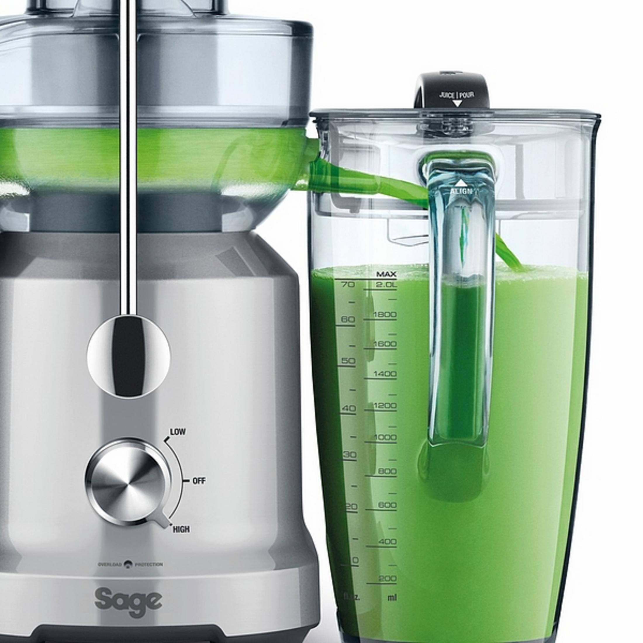 Centrifuga d'argento con un contenitore. Il succo verde scorre nel contenitore. Il marchio è Sage.