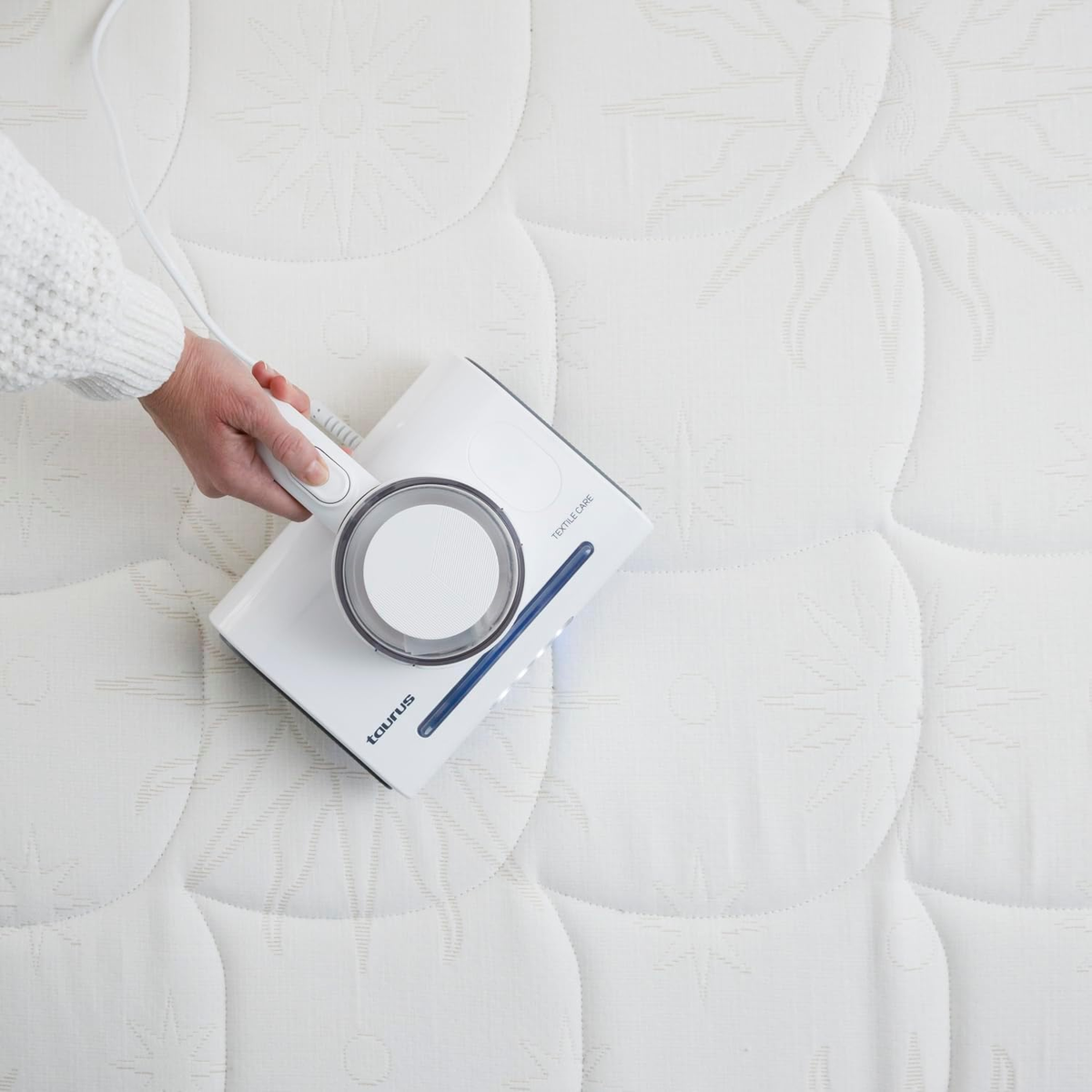 Osoba czyszcząca biały materac białym urządzeniem czyszczącym.