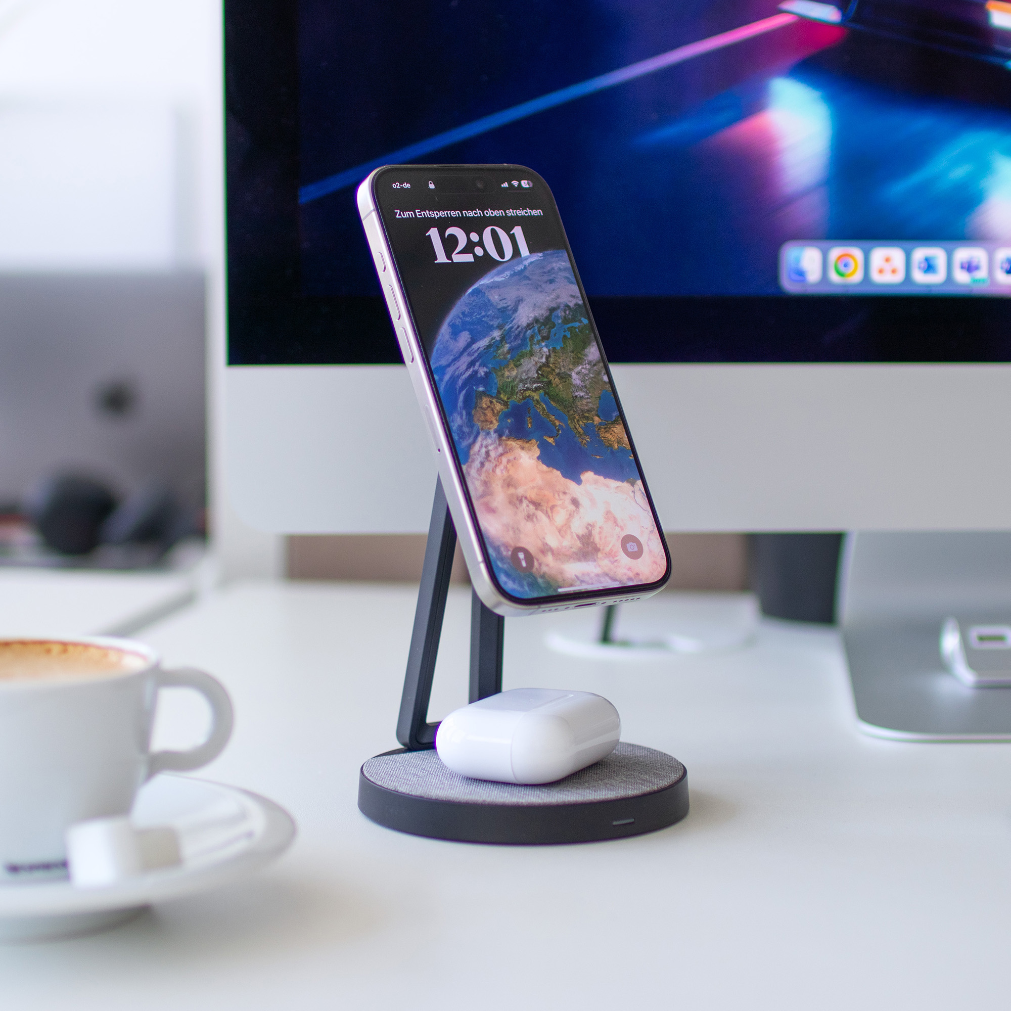 Smartphone auf einer Ladestation, mit einer Tasse Kaffee und anderen Gegenständen.
