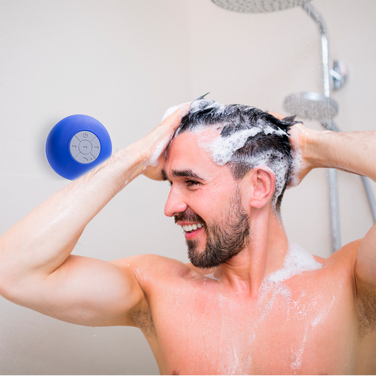 Un hombre en la ducha, lavándose el pelo, con un altavoz azul impermeable montado en la pared.