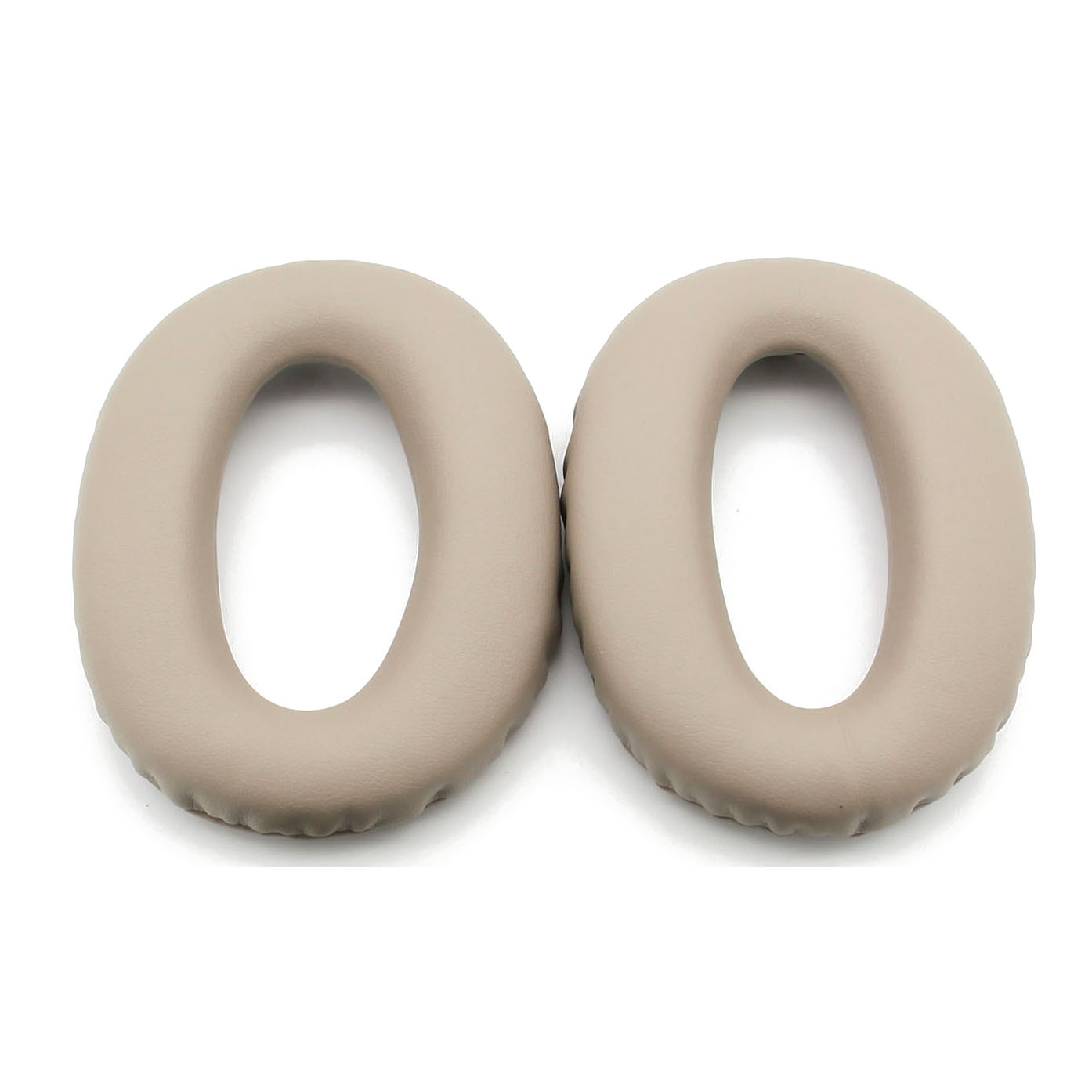 Dwie beżowe, owalne poduszki nauszne do słuchawek.