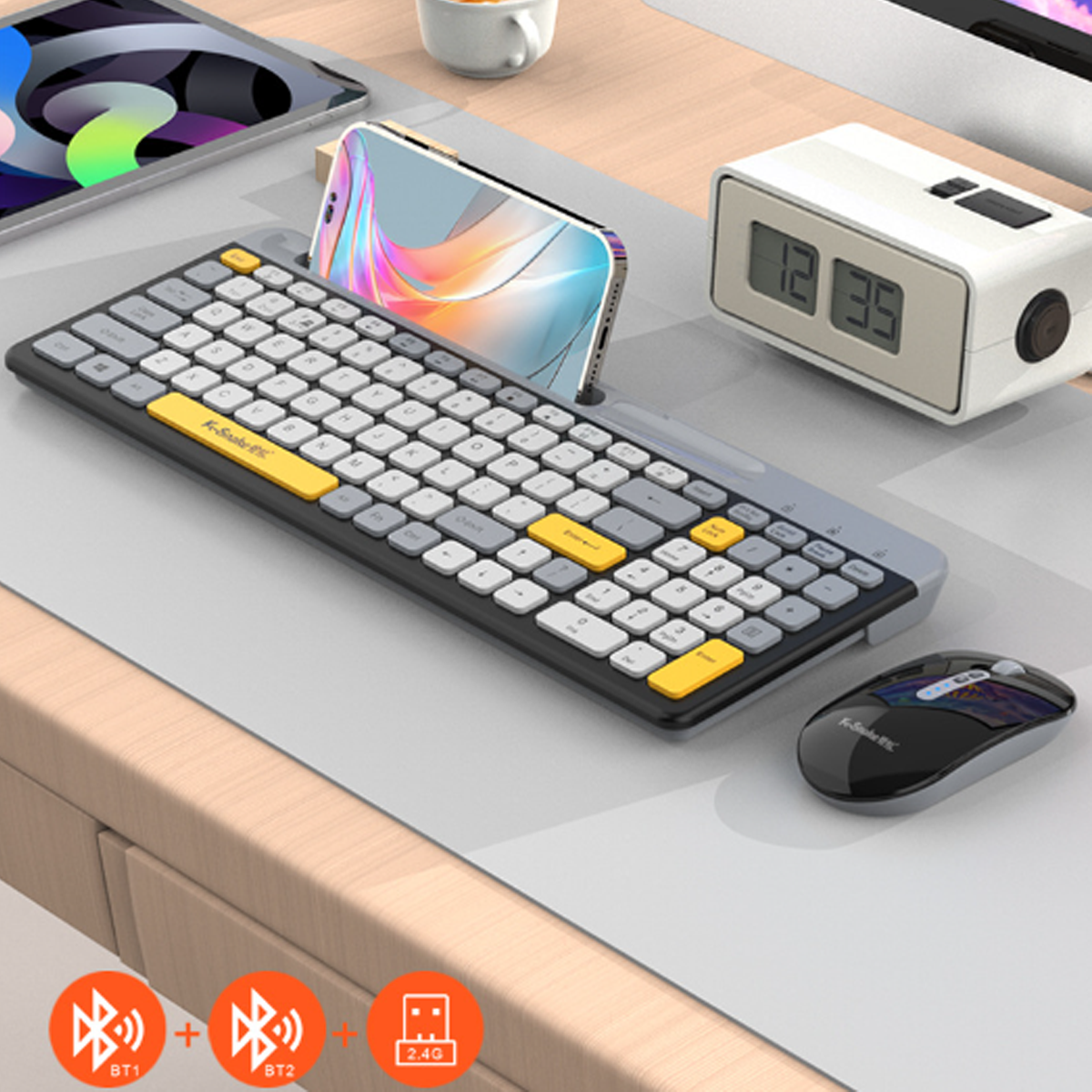 Klawiatura, mysz, telefon i zegar na jasnoszarej podkładce na biurko. Klawiatura ma żółte akcenty.