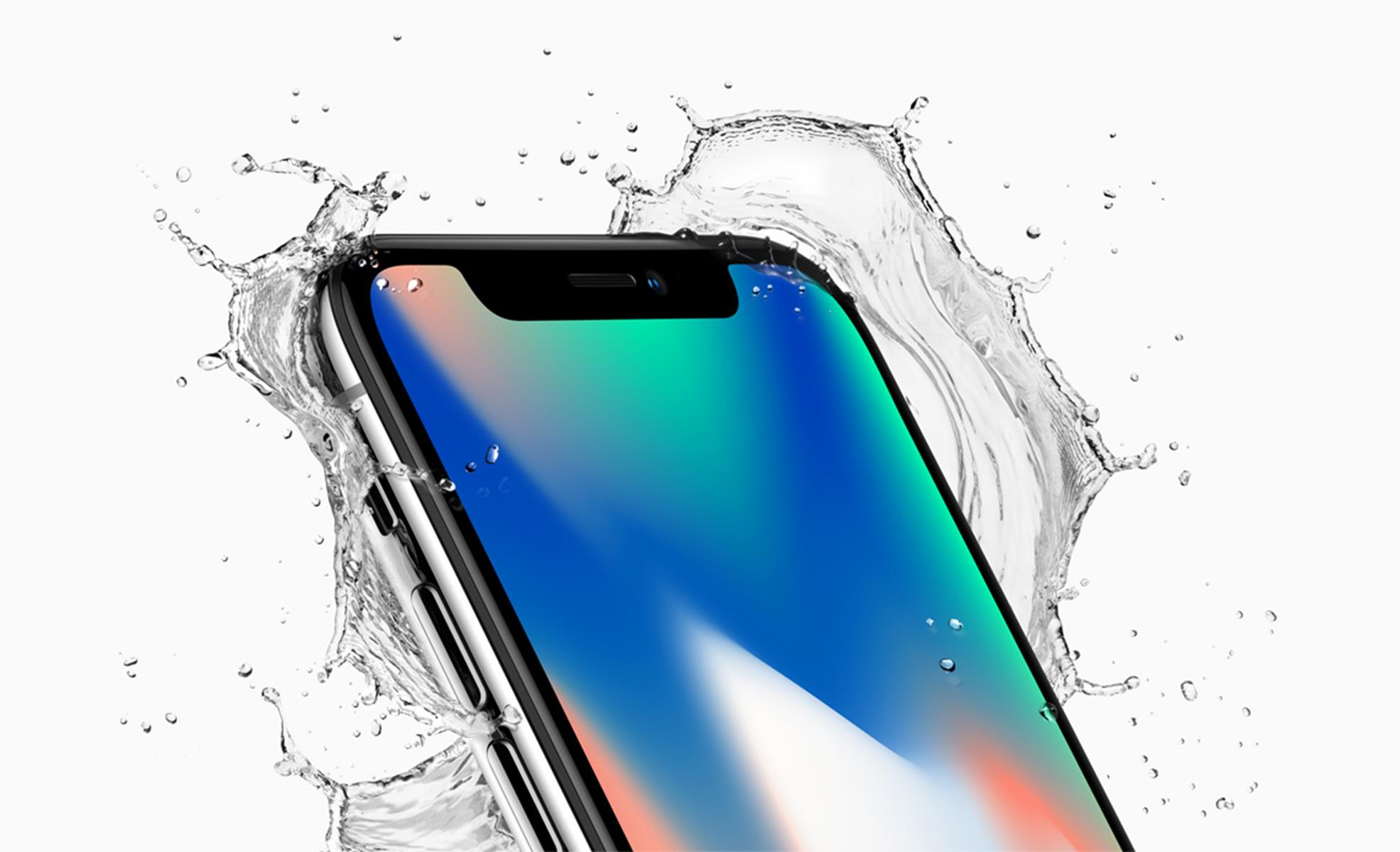 Primer plano de un teléfono salpicado de agua. El teléfono es negro y el agua clara.