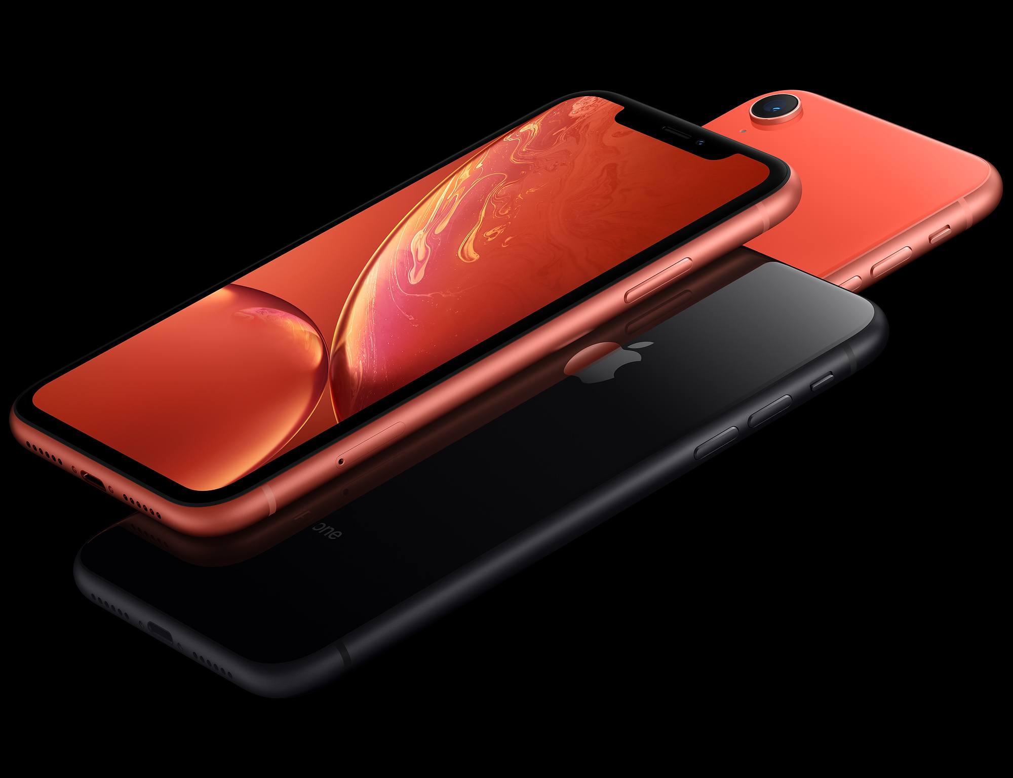 Drie iPhones, twee oranje en een zwarte, met een zwarte achtergrond.