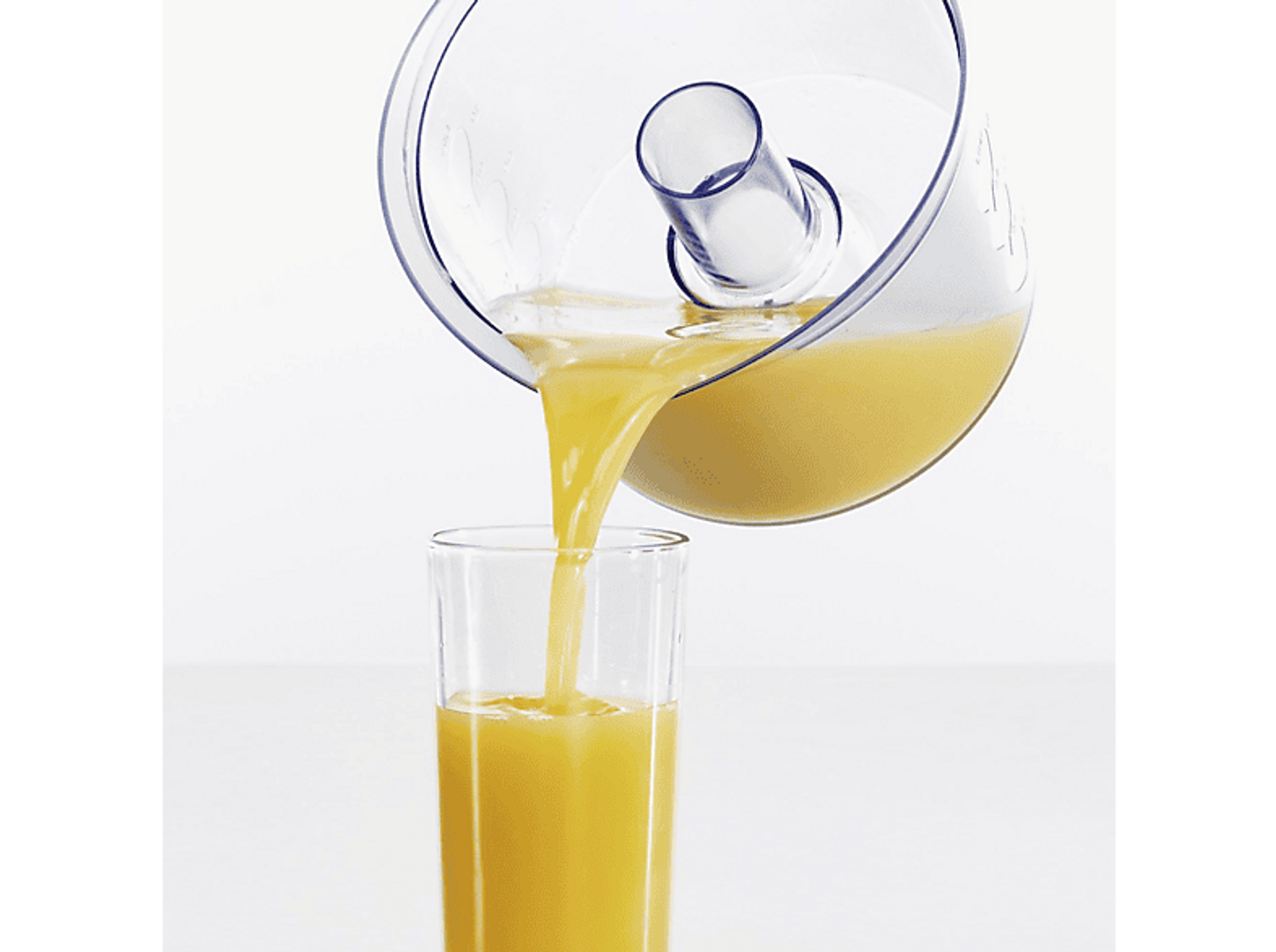 Succo d'arancia versato da un contenitore trasparente in un bicchiere.