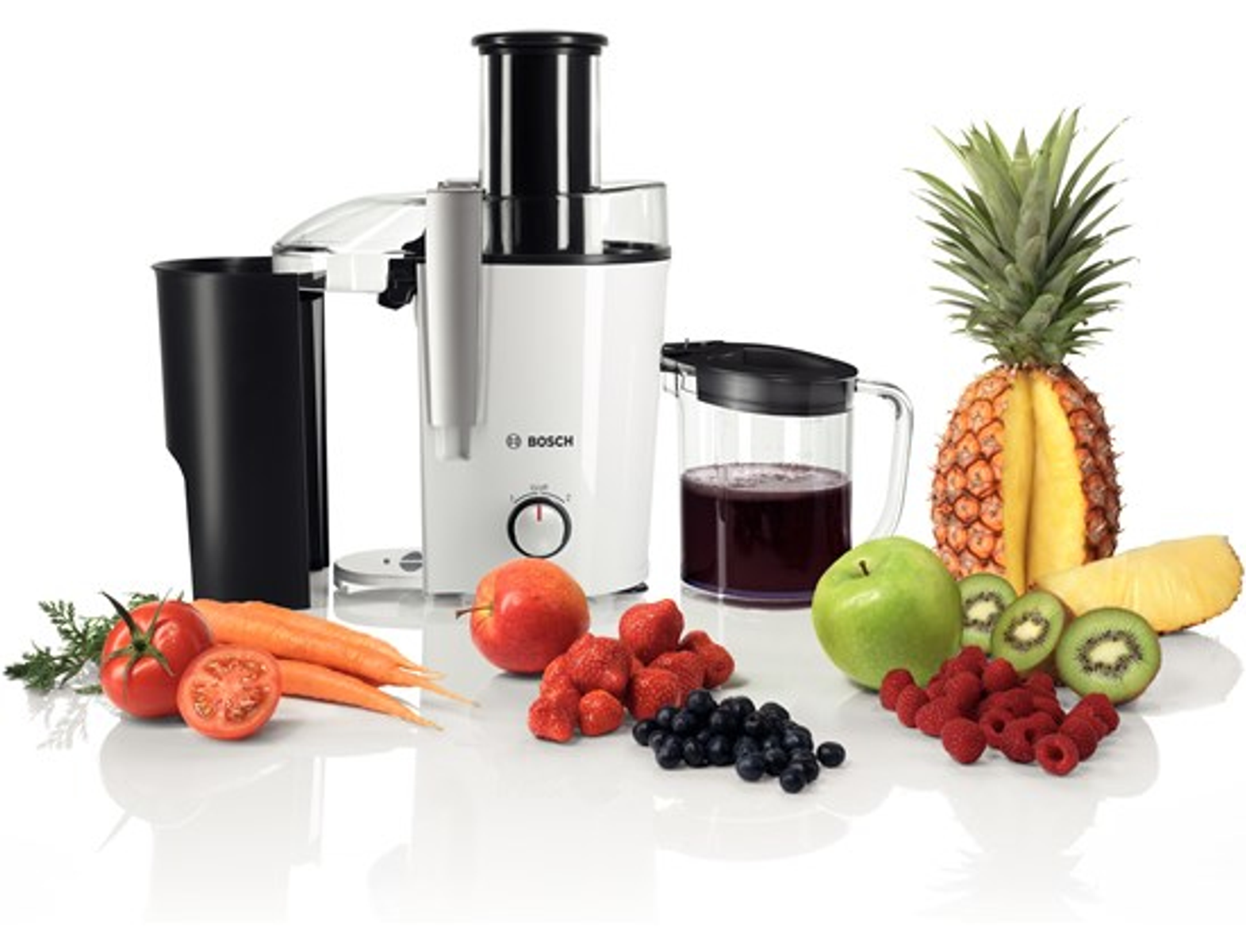 Un extracteur de jus avec des fruits comme l'ananas, la pomme, le kiwi, les fraises et les myrtilles.