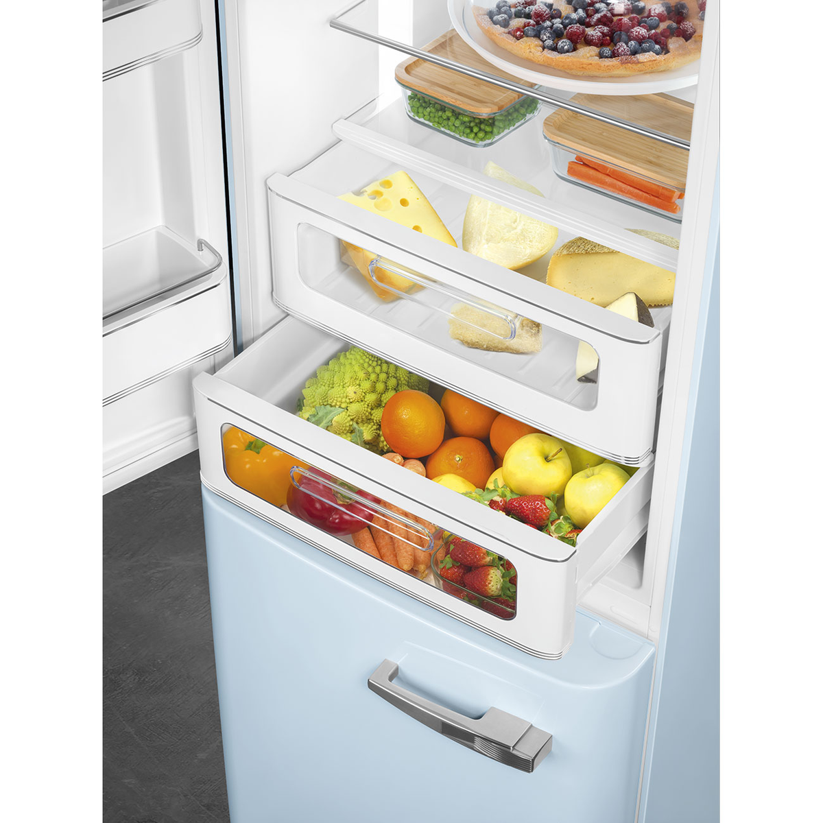 Cajones de refrigerador llenos de frutas, verduras, queso y recipientes de alimentos. Refrigerador azul.