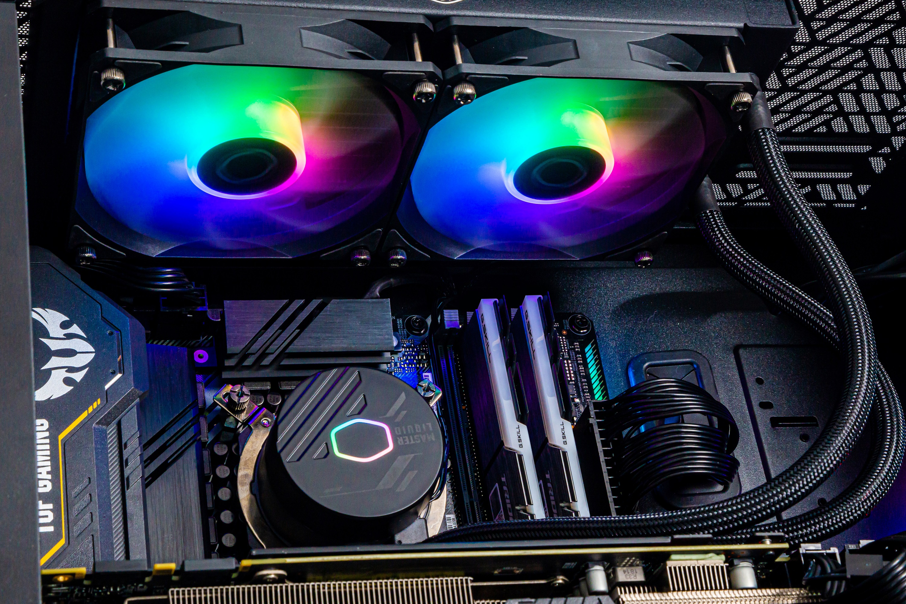 Wewnątrz komputera z wentylatorami RGB i elementami chłodzenia wodnego. Komponenty są podświetlone.