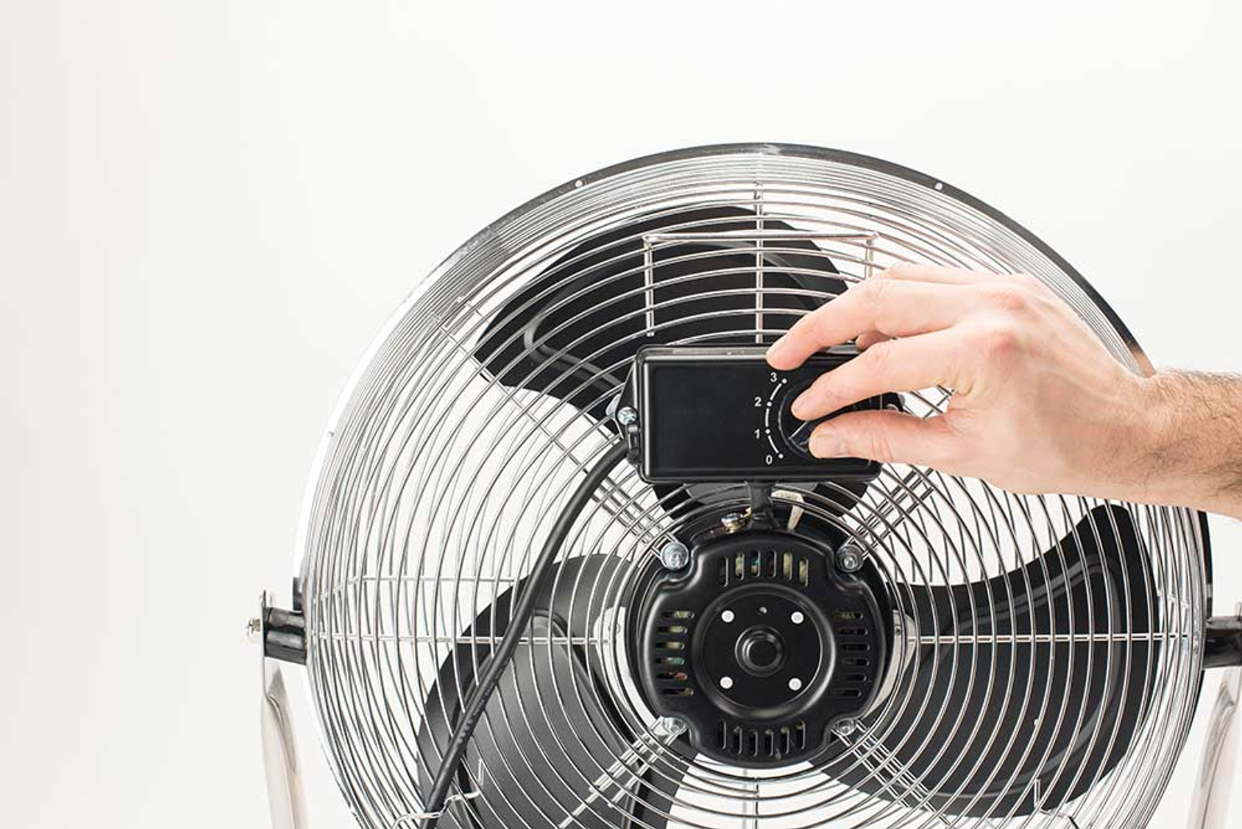 Mano che regola la manopola della velocità su un ventilatore in metallo.