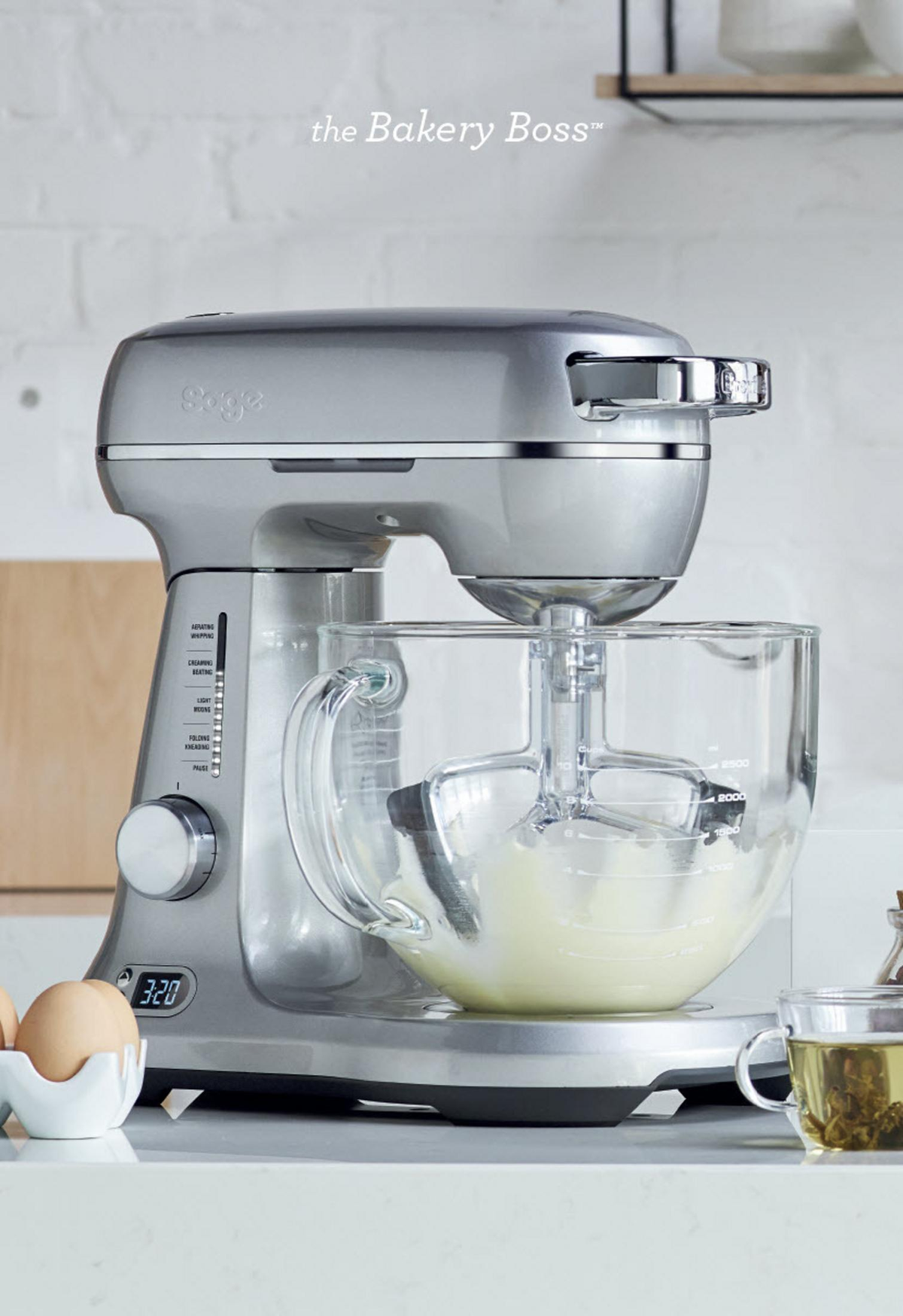 Ein silberner Küchenmixer mit einer Glasschüssel. Der Mixer steht auf einer weißen Oberfläche.