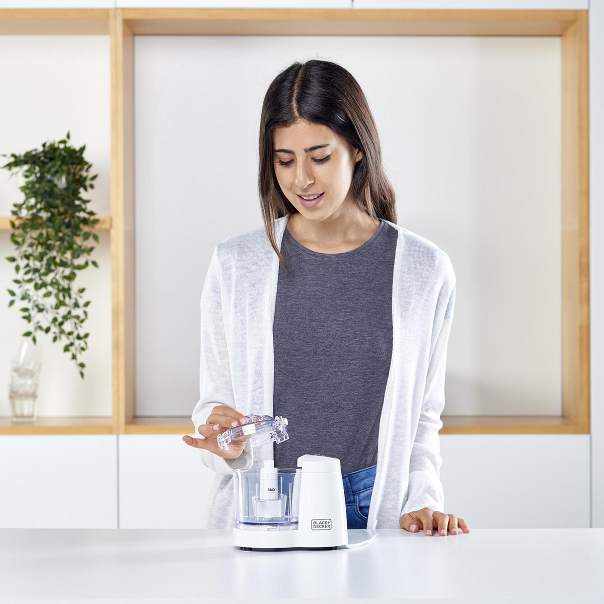 Donna che usa un robot da cucina in cucina. Un robot da cucina Black + Decker è sul tavolo.