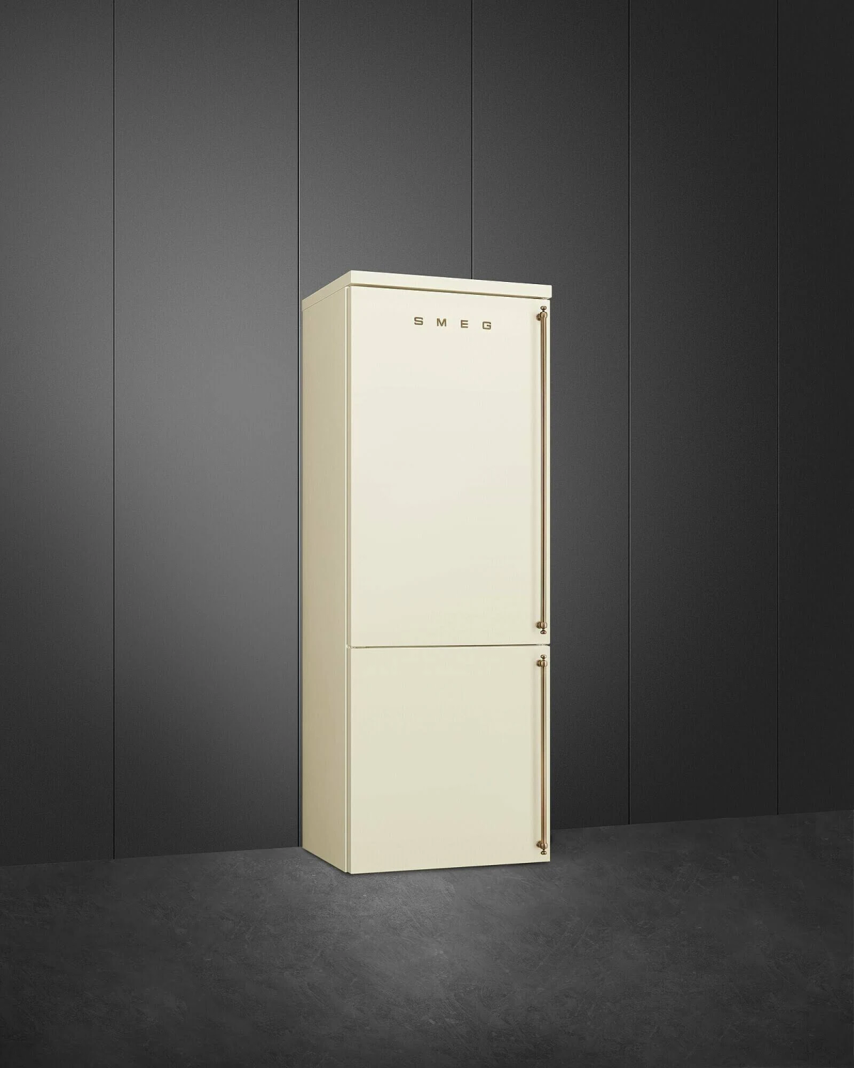 Un frigorífico SMEG color crema con tiradores dorados contra una pared oscura.