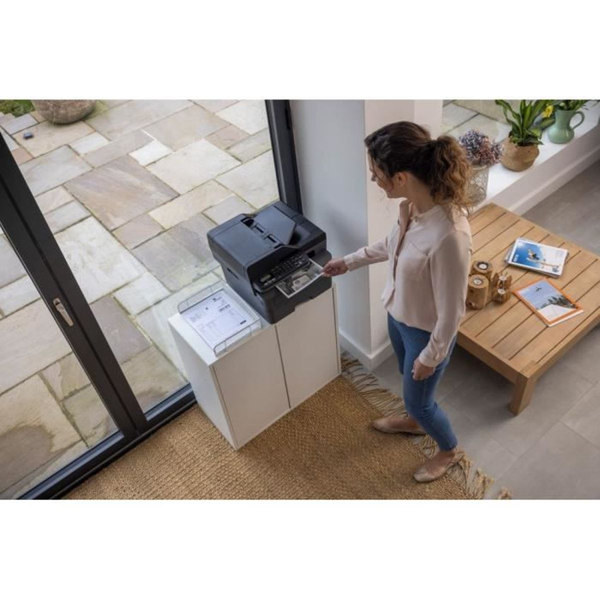 Kobieta korzystająca z drukarki. Drukarka stoi na białej szafce.