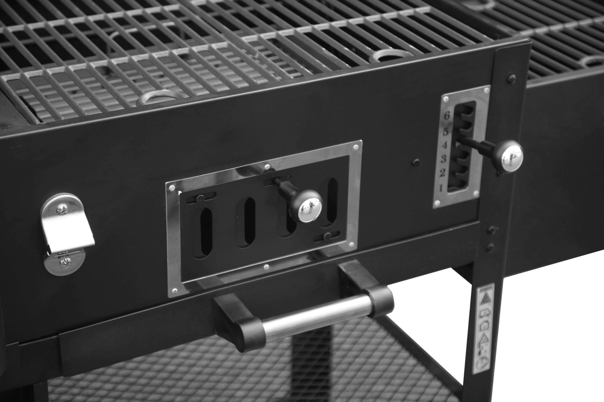 Nahaufnahme eines schwarzen Grills mit Griff, Bedienhebeln und Lüftungsschlitzen. Metallroste.