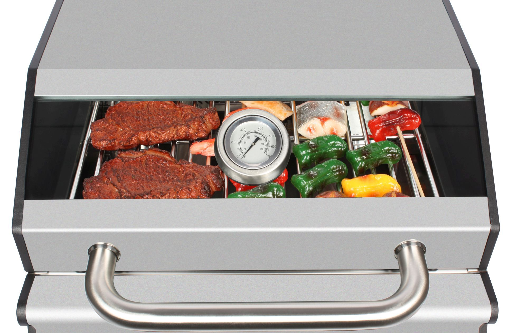 Grill mit Steaks, Gemüse und einem Thermometer im Inneren.