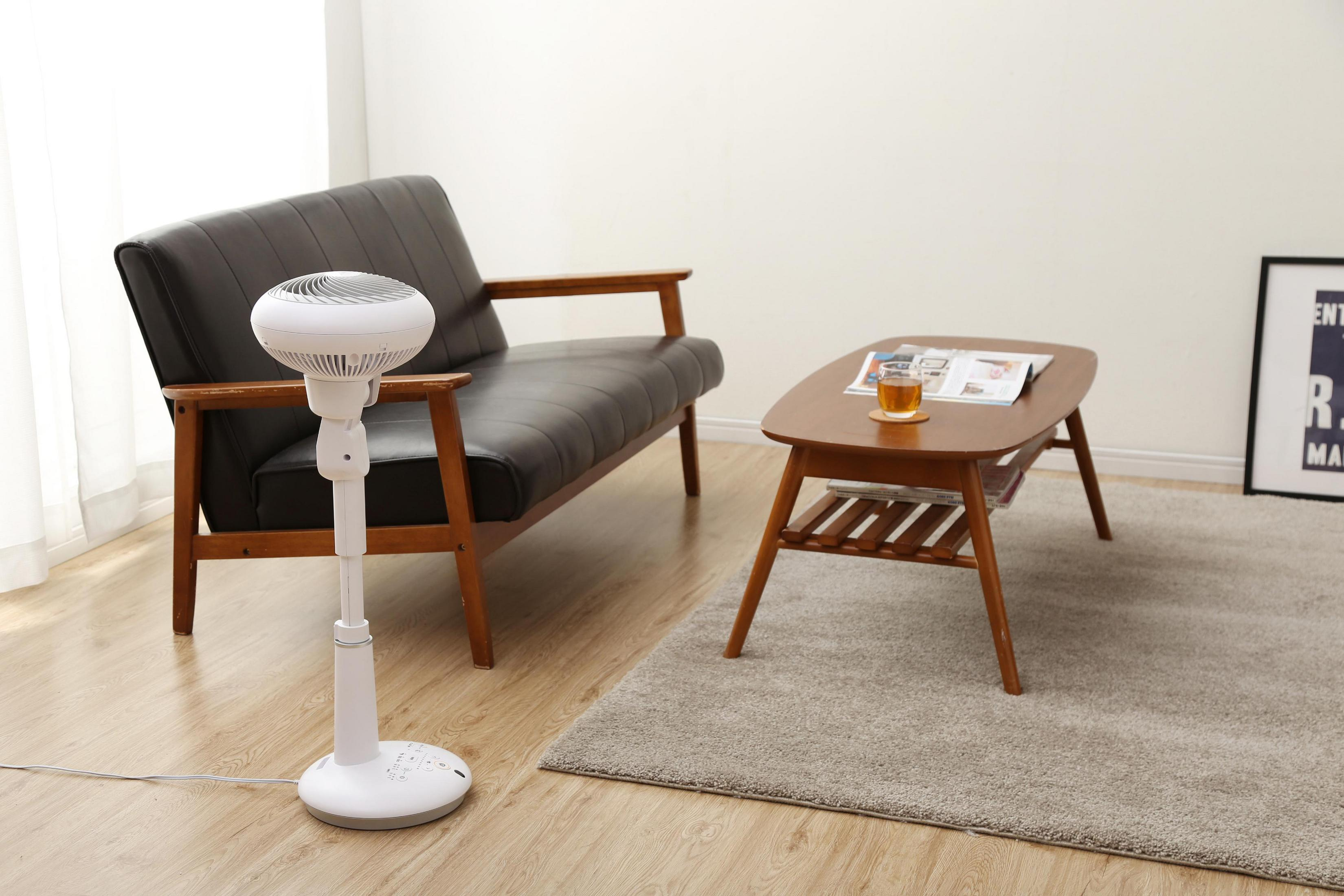 Habitación con ventilador, sofá y mesa de centro. Hay un vaso de té en la mesa.