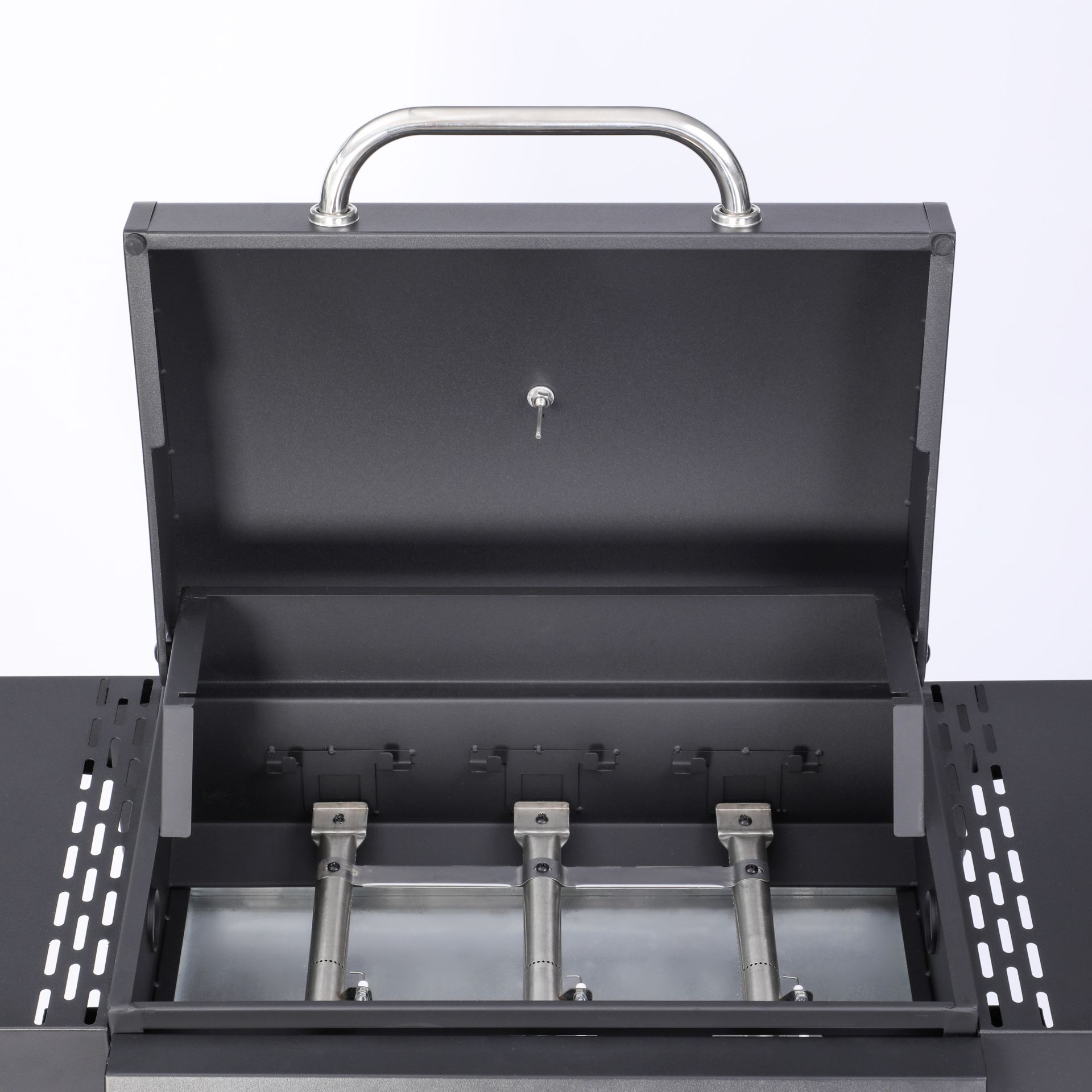 Nahaufnahme eines schwarzen Grills mit offenem Deckel, der die Brenner zeigt. Weißer Hintergrund.