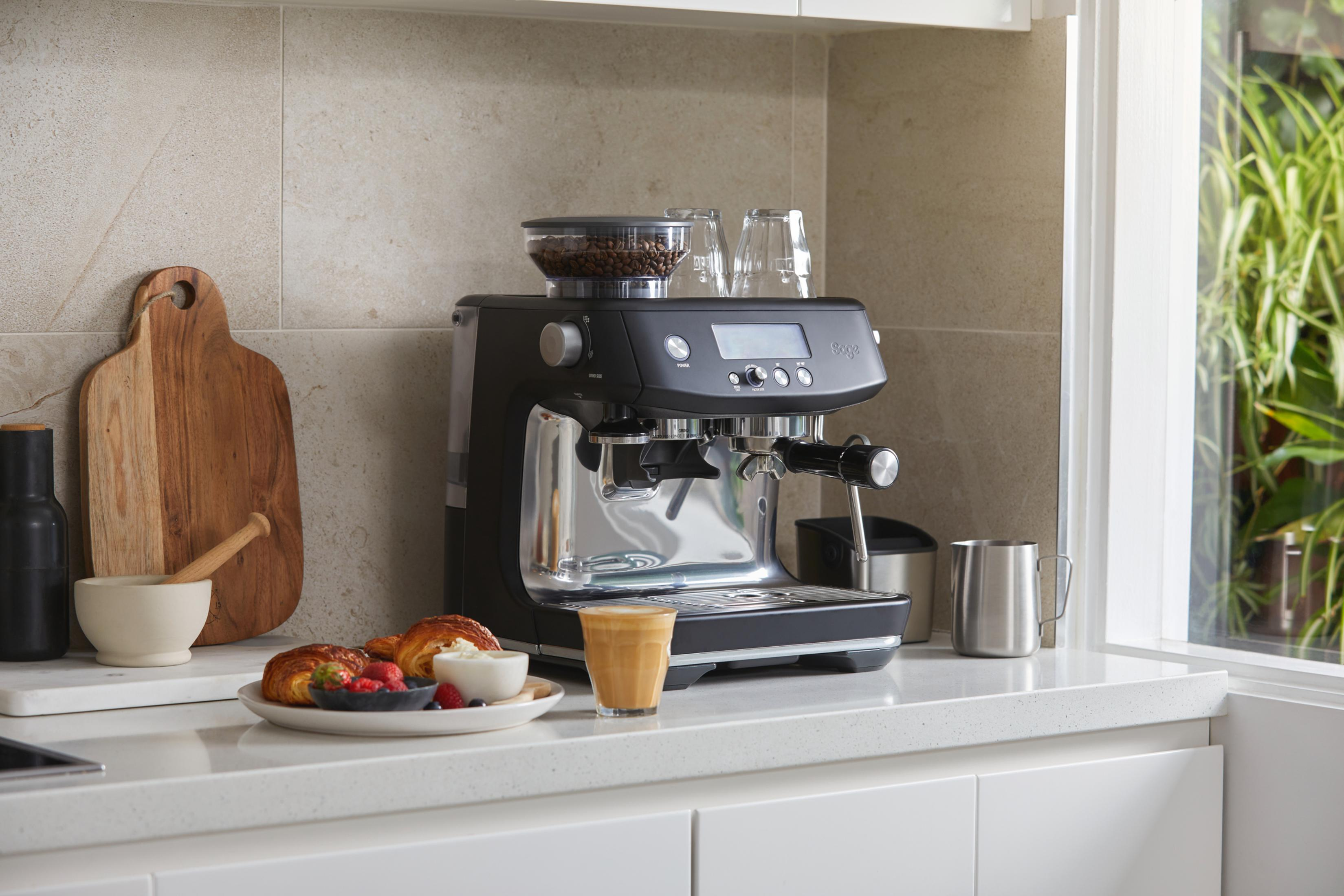 Espressomaschine auf Arbeitsplatte mit Kaffee, Gebäck und Blick aus dem Fenster.
