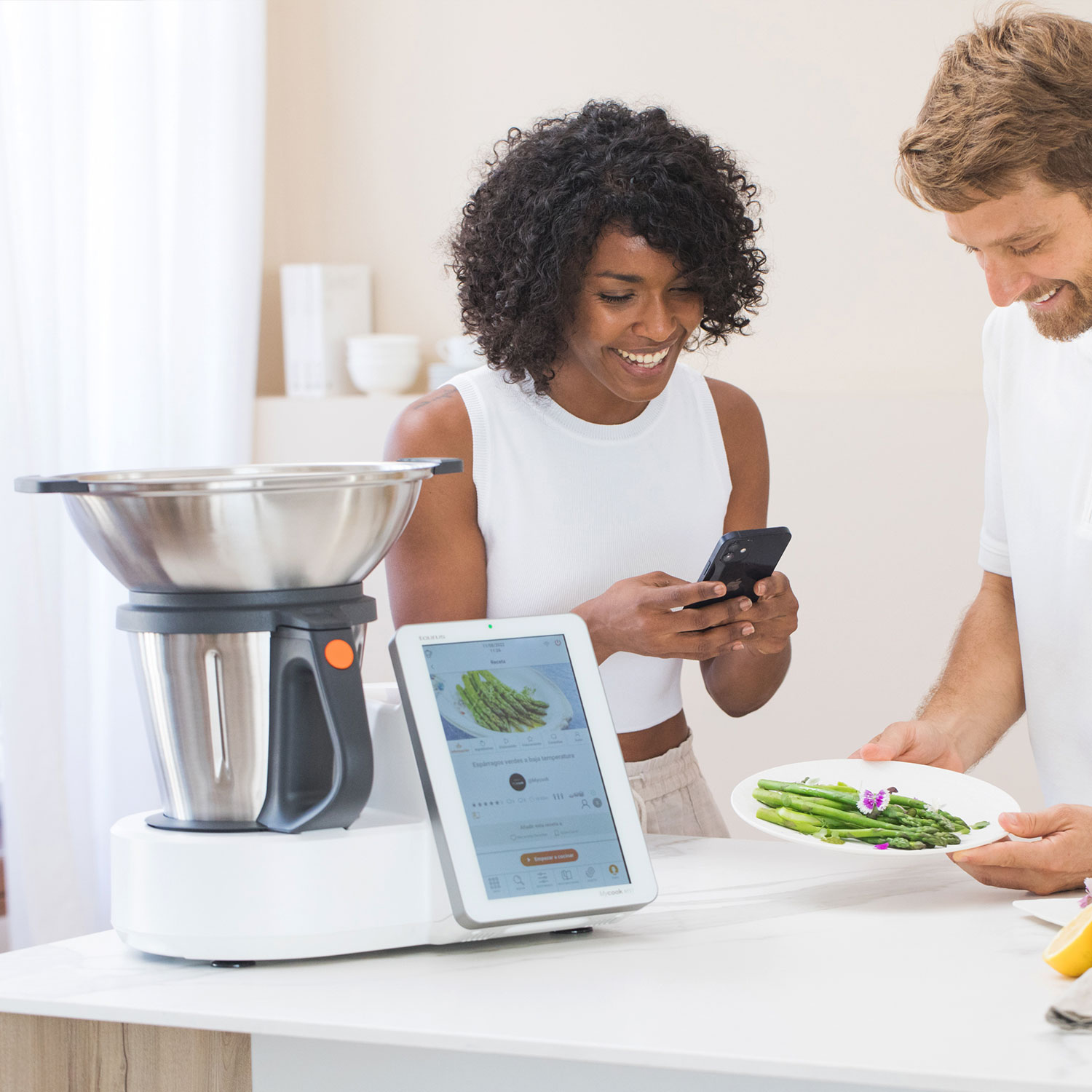 Una pareja está preparando comida con un electrodoméstico de cocina inteligente, usando una tableta.