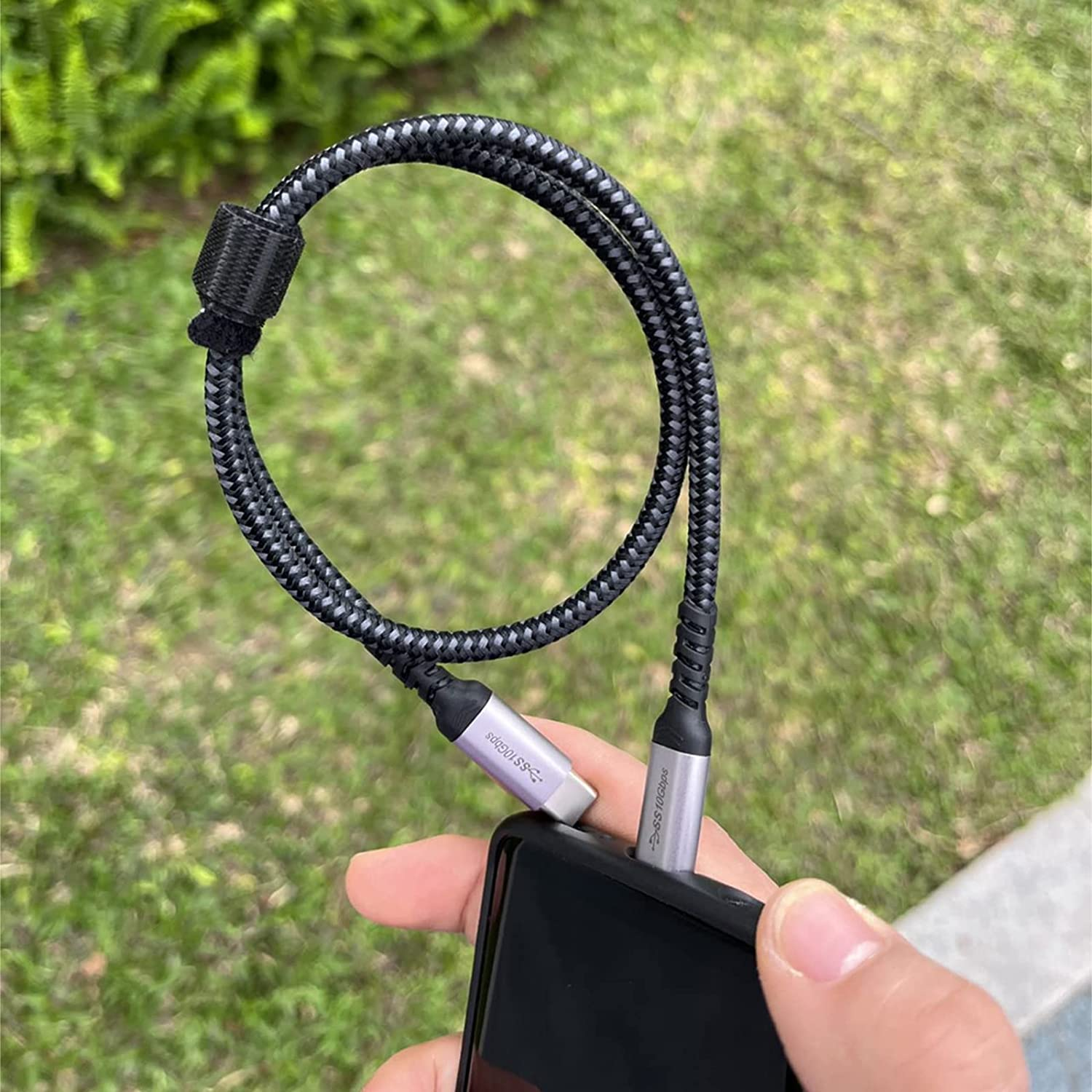 Kabel USB-C jest podłączony do telefonu. Kabel ma czarną plecioną teksturę.