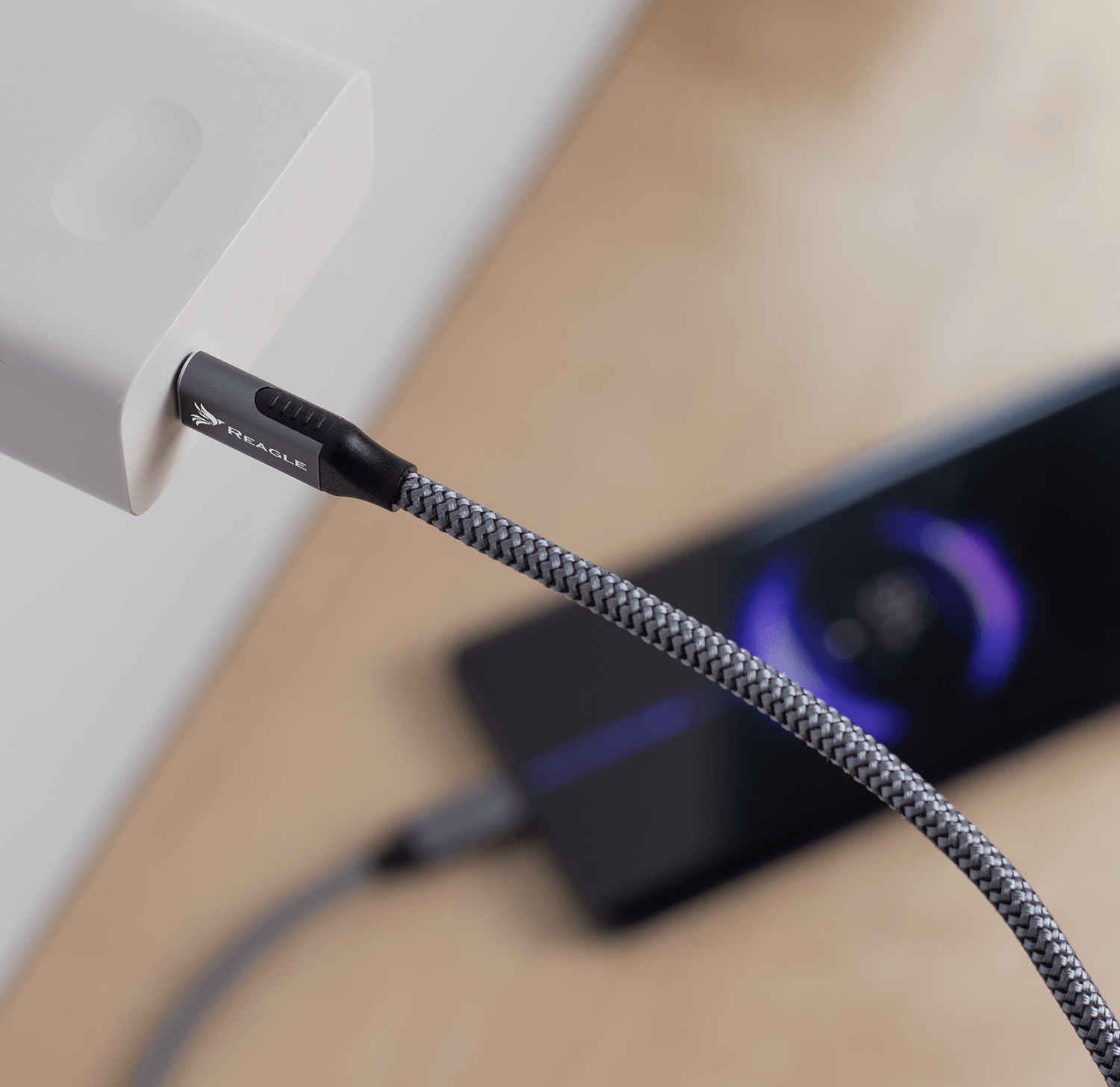 Telefon ładujący się za pomocą szarego kabla podłączonego do power banku.