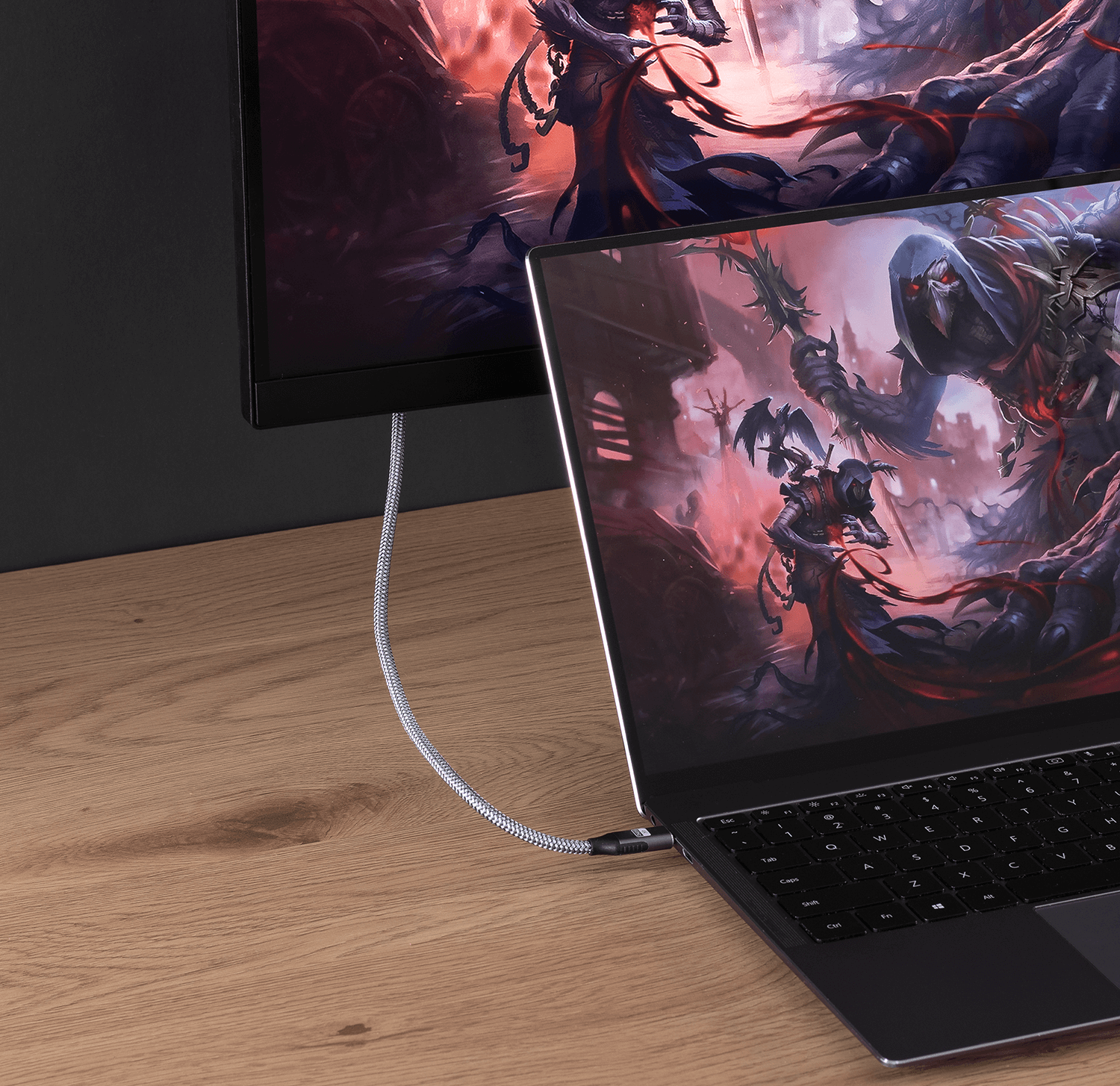 Laptop podłączony do monitora za pomocą srebrnego kabla. Monitor wyświetla scenę z gry.